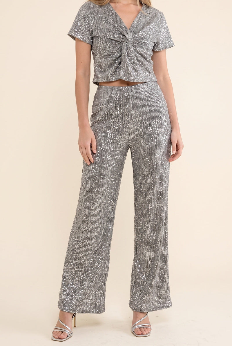 Silver sequin two-piece set with a twist-front crop top and wide-leg pants, a festive cocktail attire outfit.