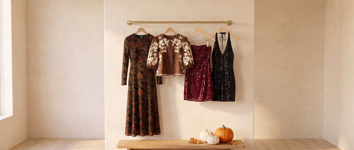 New this October on a brass rail: a green velvet burnout floral maxi dress, a brown faux suede top with cream embroidered flowers, a wine strapless sequin mini dress and a black sequin halter mini dress, small pumpkins on a bench below