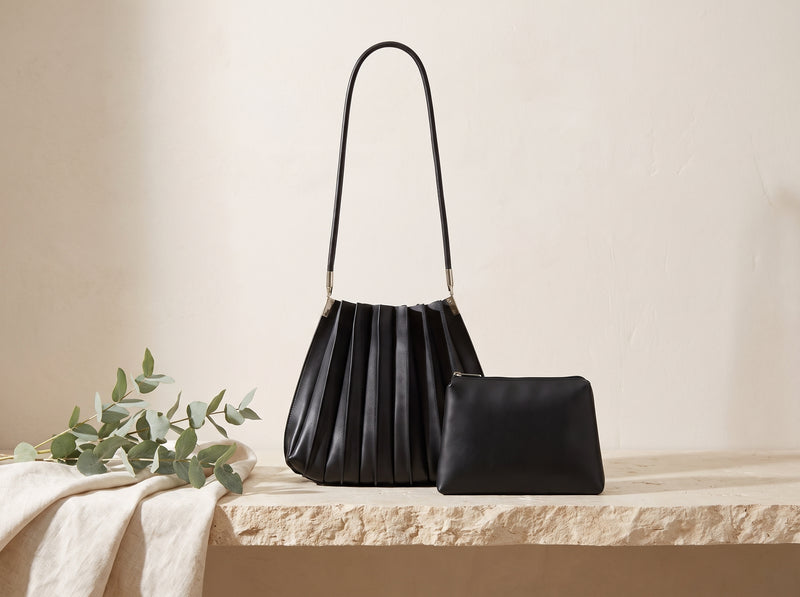 Black pleated vegan leather shoulder bag in a still life