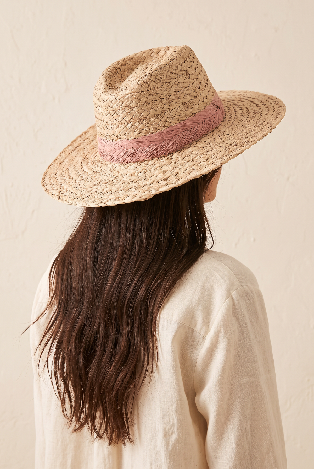 Lyla braided straw fedora with a pink leaf-braid band, worn, seen from behind over a cream linen shirt