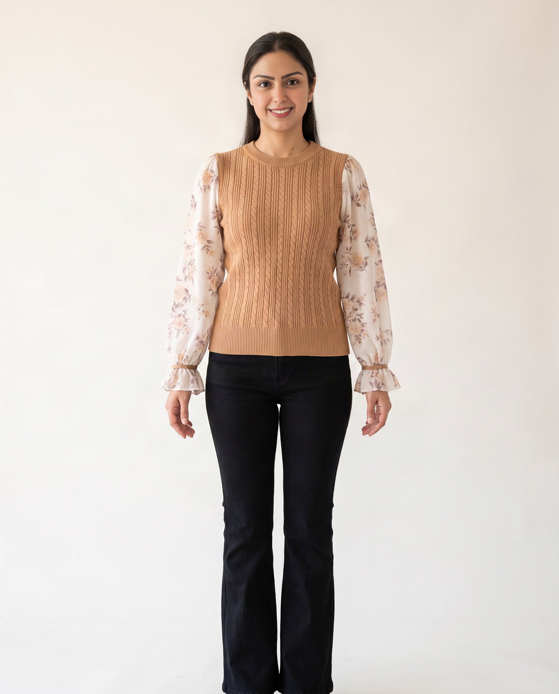 Shweta wearing the Medium Tan knit sweater top with floral sleeves and black flared jeans.