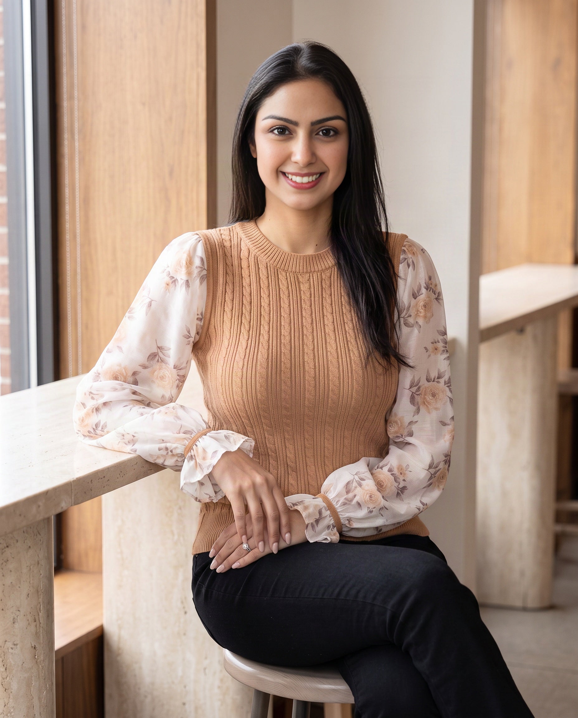 Shweta styling the Tan floral-sleeve knit sweater with black flared jeans in a daylight café.