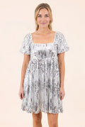 Front fit of the silver sequin babydoll dress showing its square neck, empire seam and mini length.