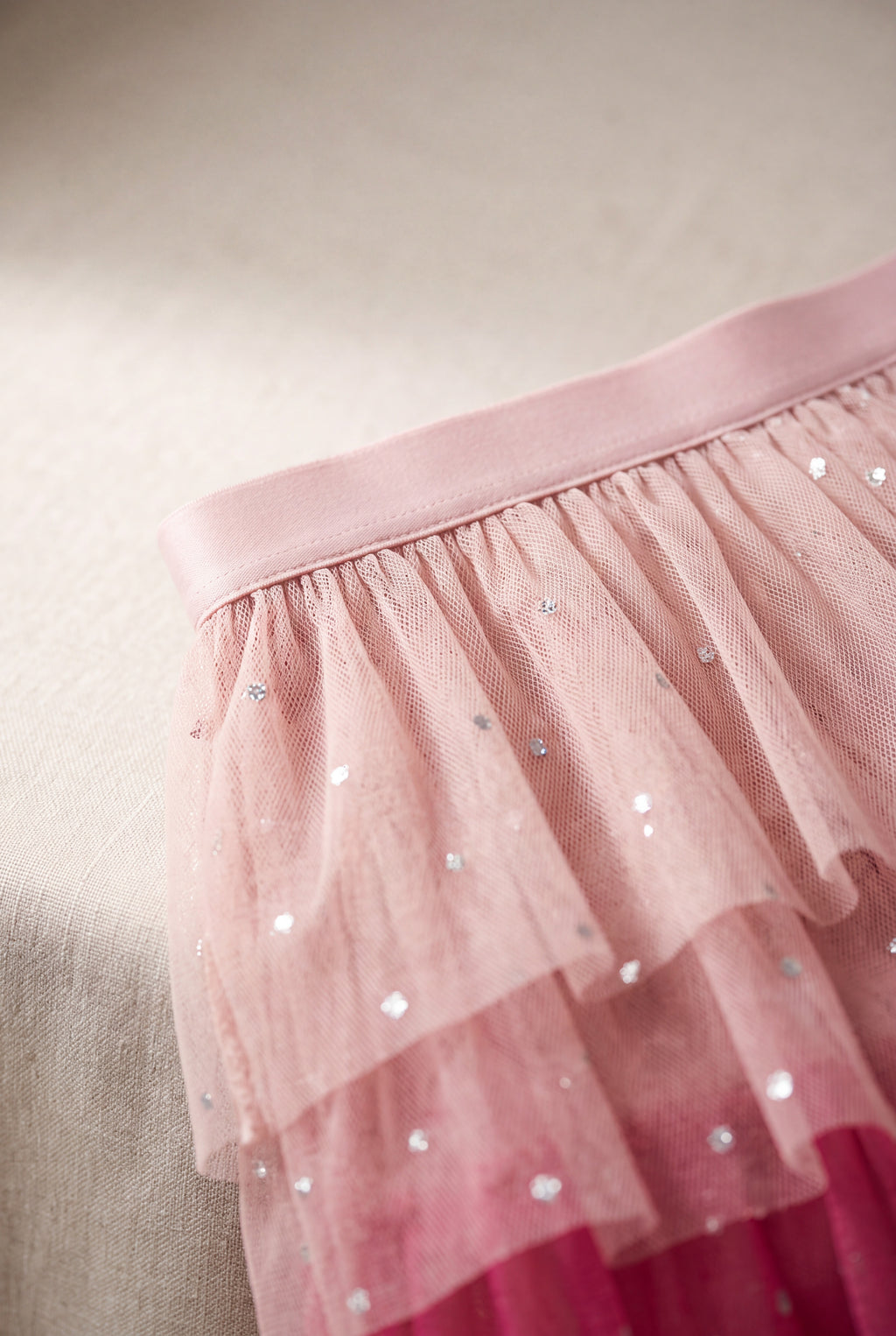 Close detail of the pink tulle skirt waistband, layered mesh and reflective dot embellishment.