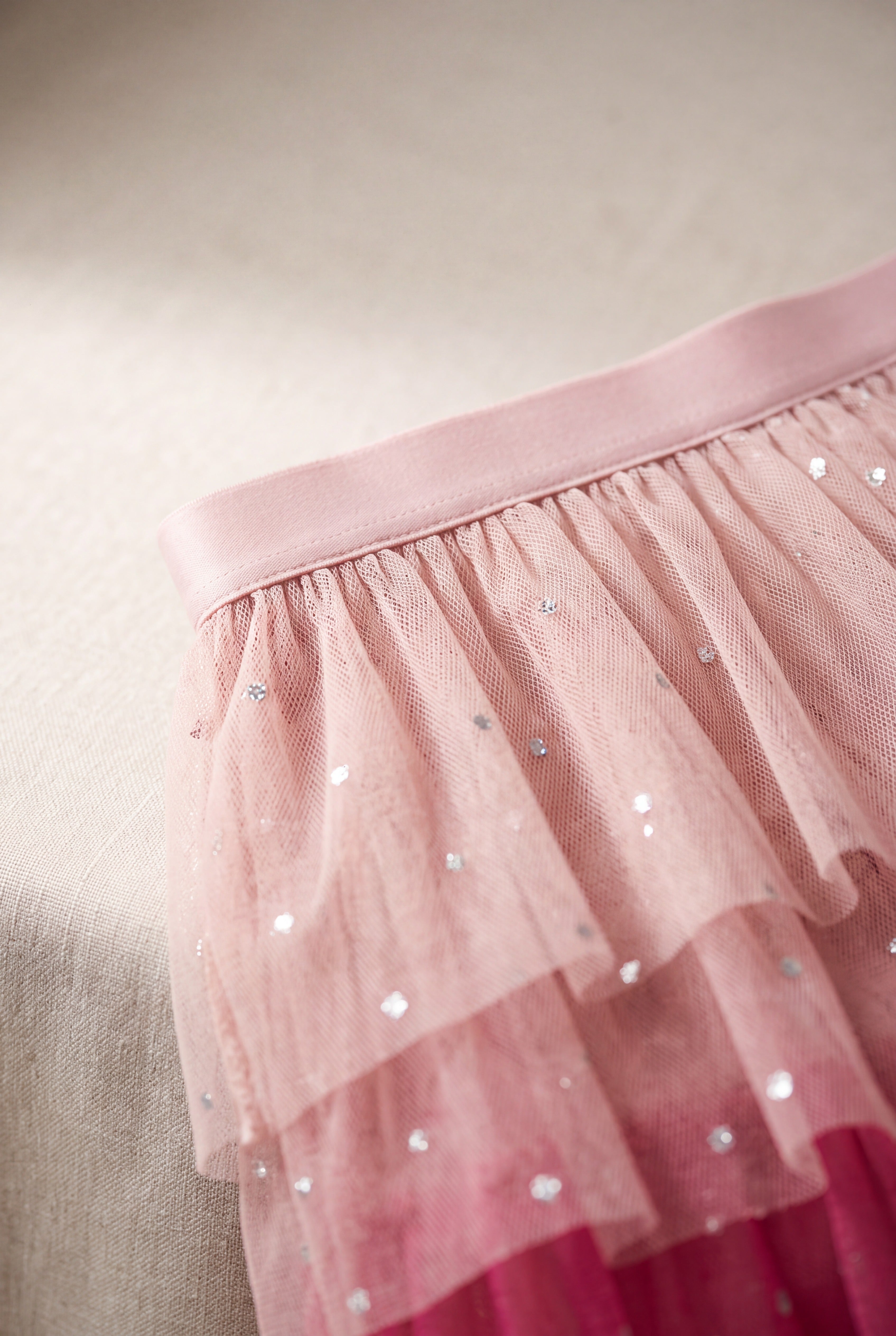 Close detail of the pink tulle skirt waistband, layered mesh and reflective dot embellishment.