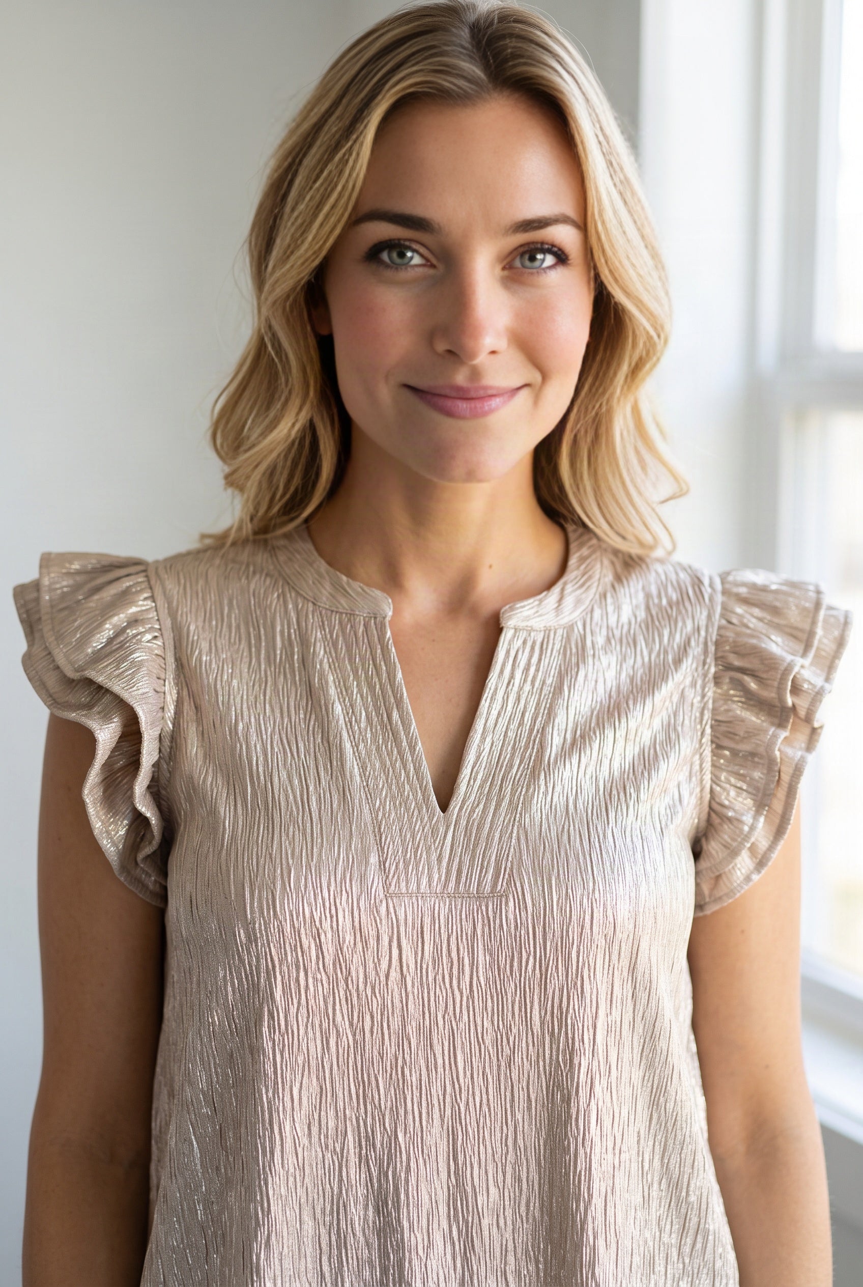 Champagne ruffle top detail showing the split neck band, front yoke seam and layered flutter sleeves.