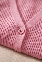 Pink cardigan close-up showing the fine rib knit, tonal button and narrow front band.