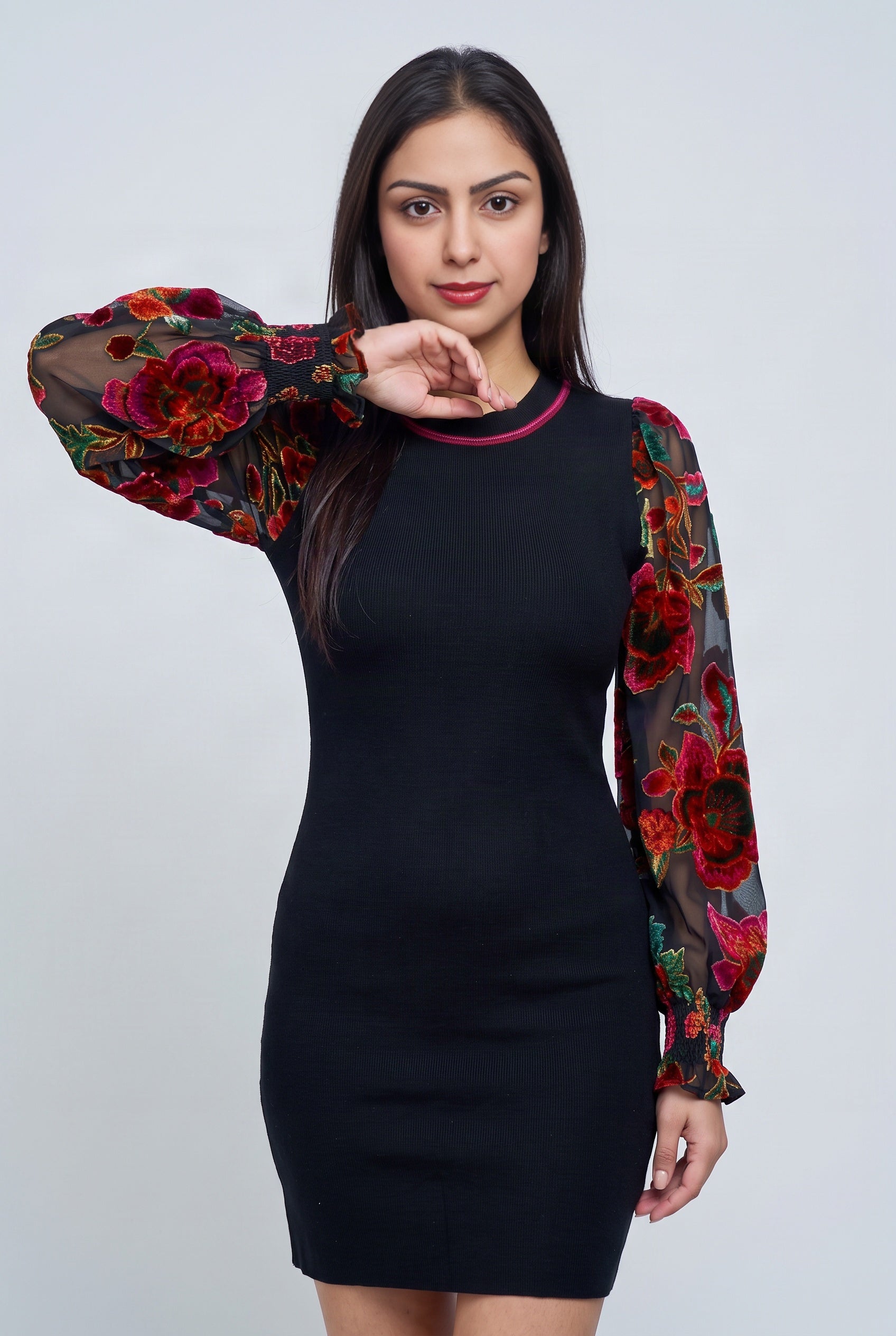 Close view of the dress's sheer floral sleeve, smocked cuff, ruffle edge, and black rib-knit body.