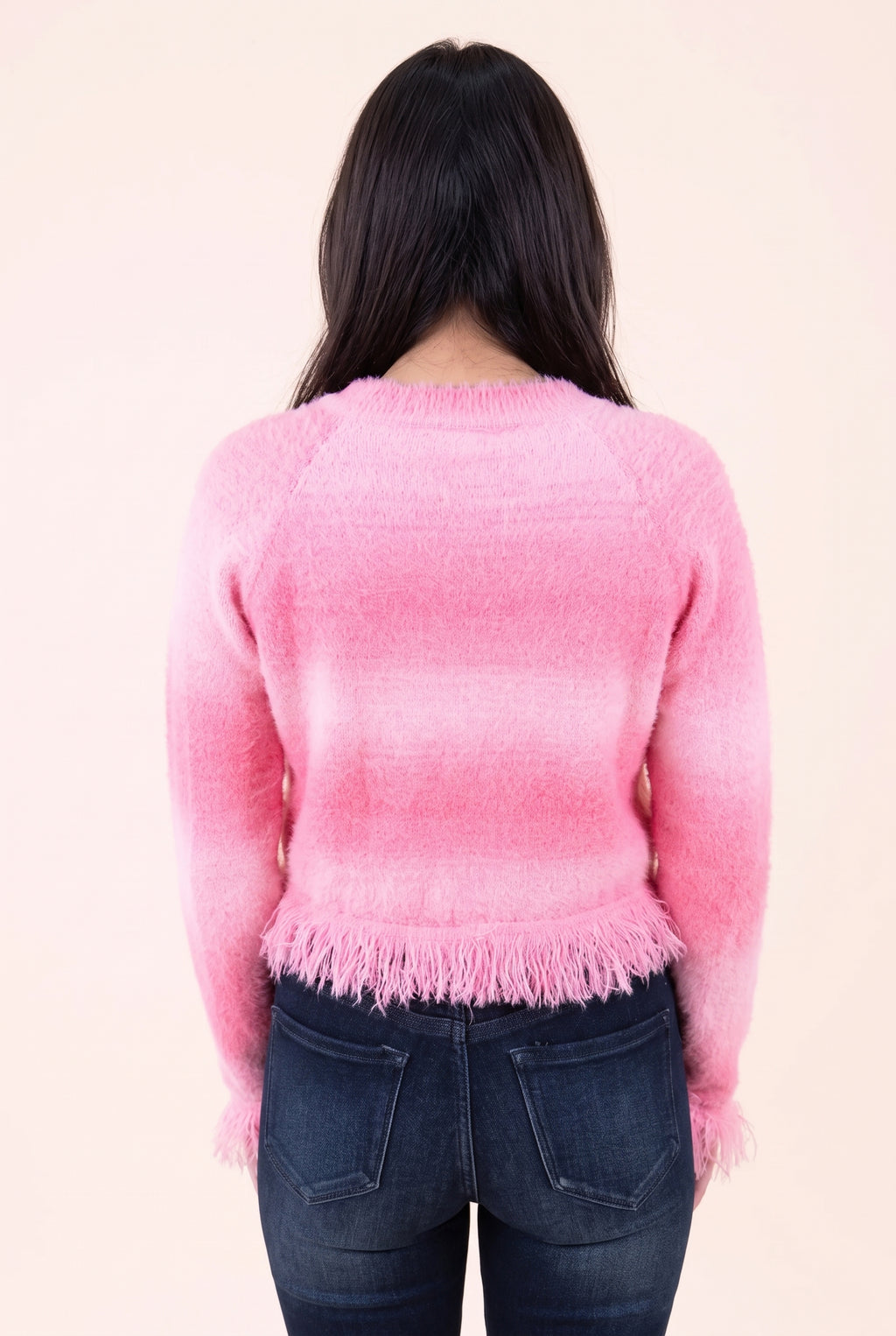 Back view of the pink cropped cardigan showing its plain back, shoulder shaping and fringed hem.