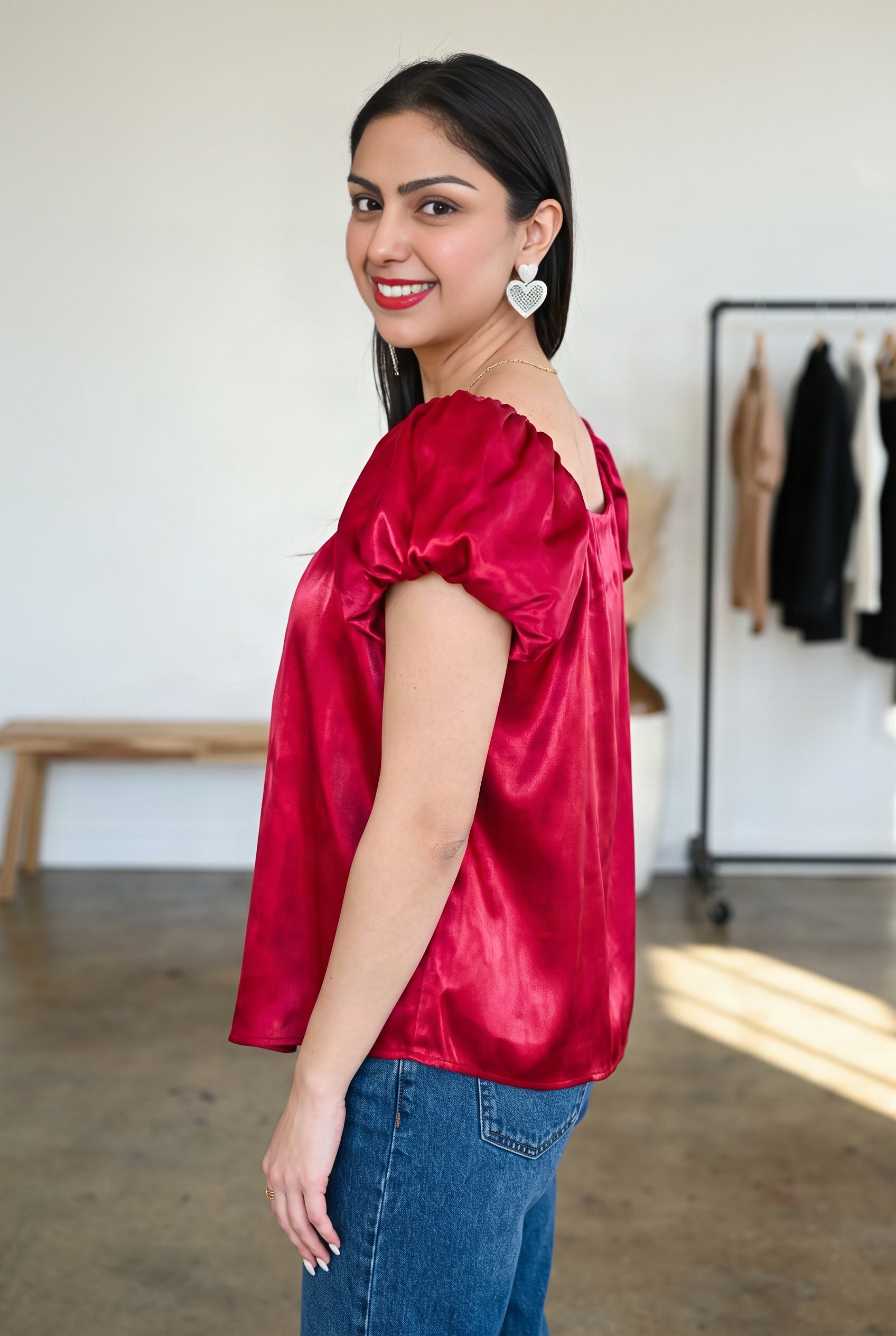 Side fit of the red satin puff sleeve top showing its projected sleeve and roomy untucked body.