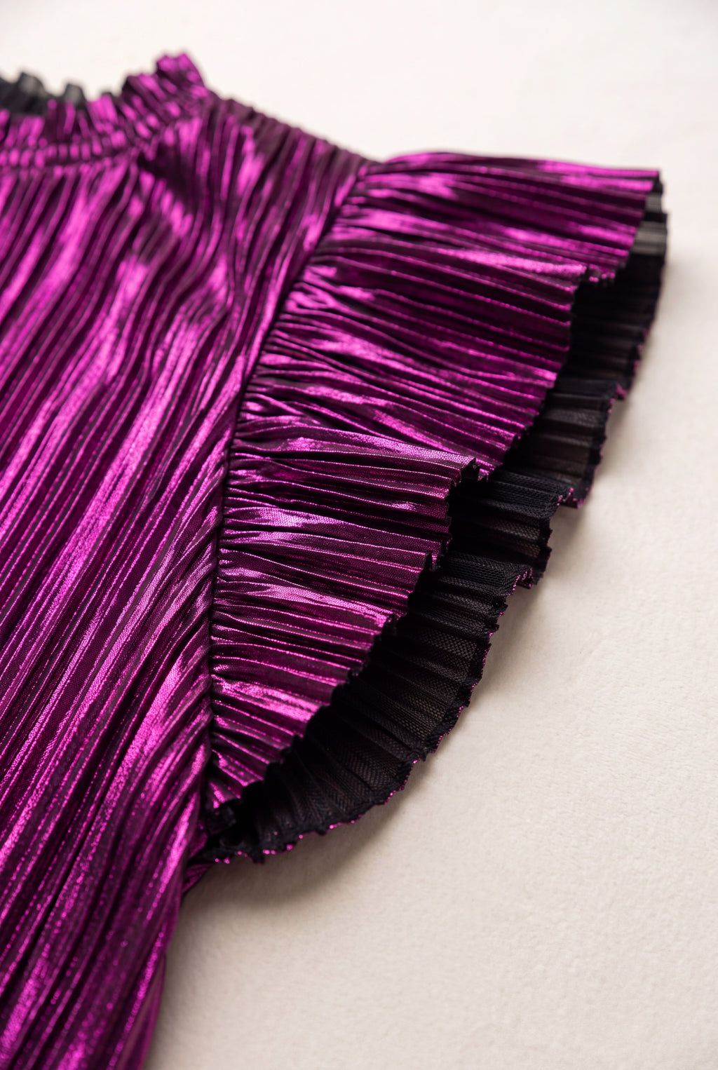 Close detail of the top’s metallic purple pleats and black-backed ruffle edge.
