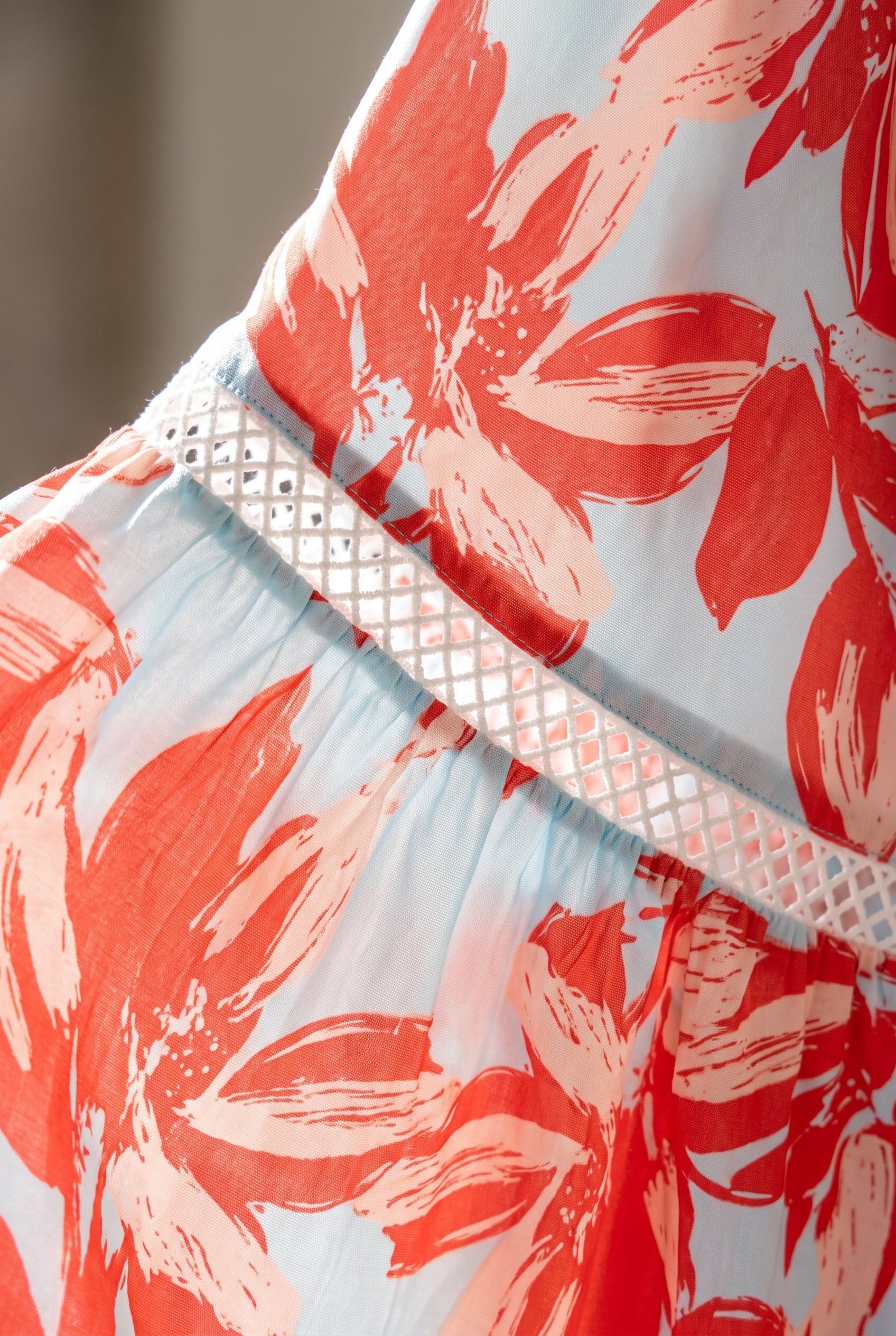 Close detail of the Painted The Sky dress showing its floral polyester and white diamond-lattice trim.