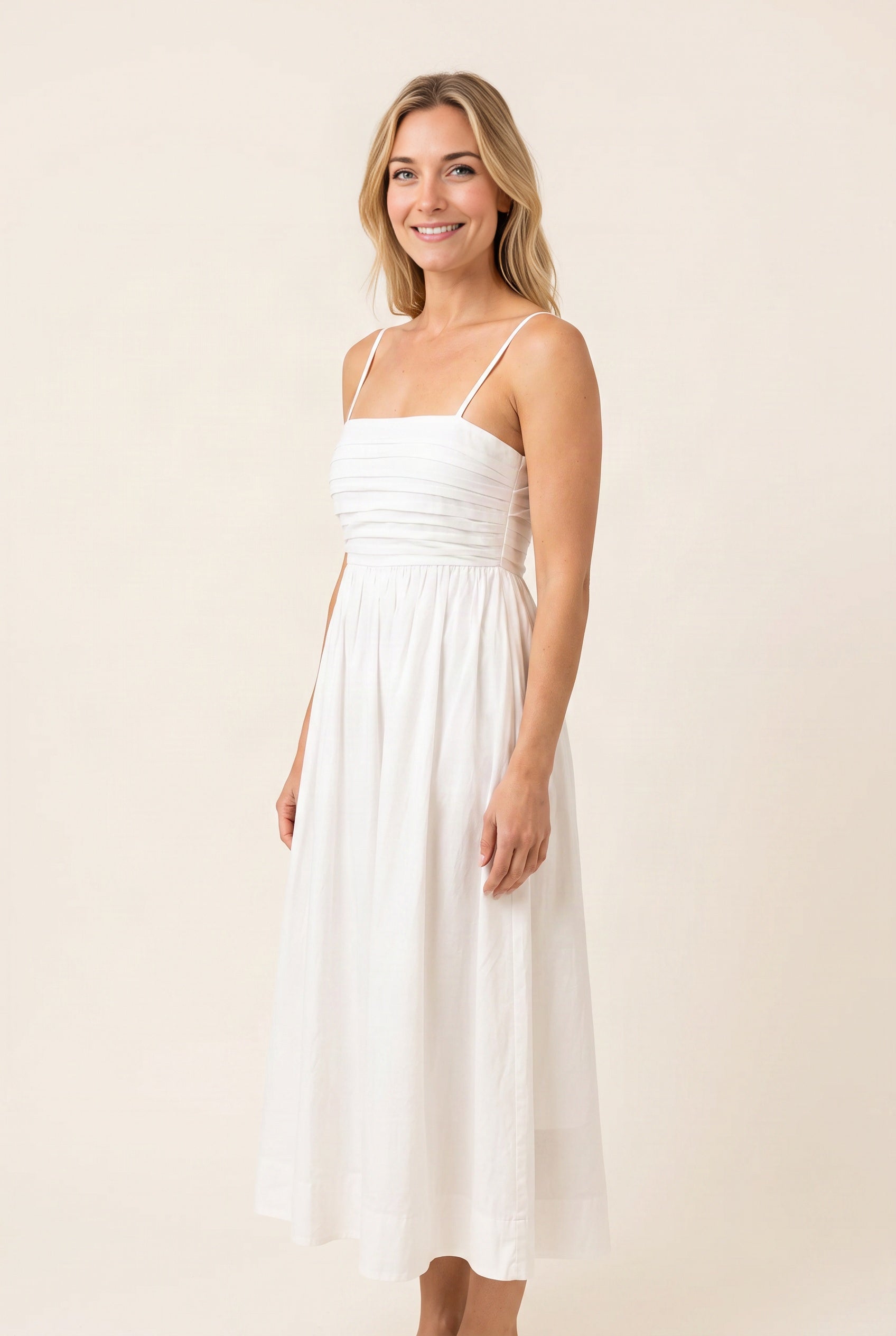 Angled side view of the Love Actually White Pleated Midi Dress showing waist placement and skirt volume.