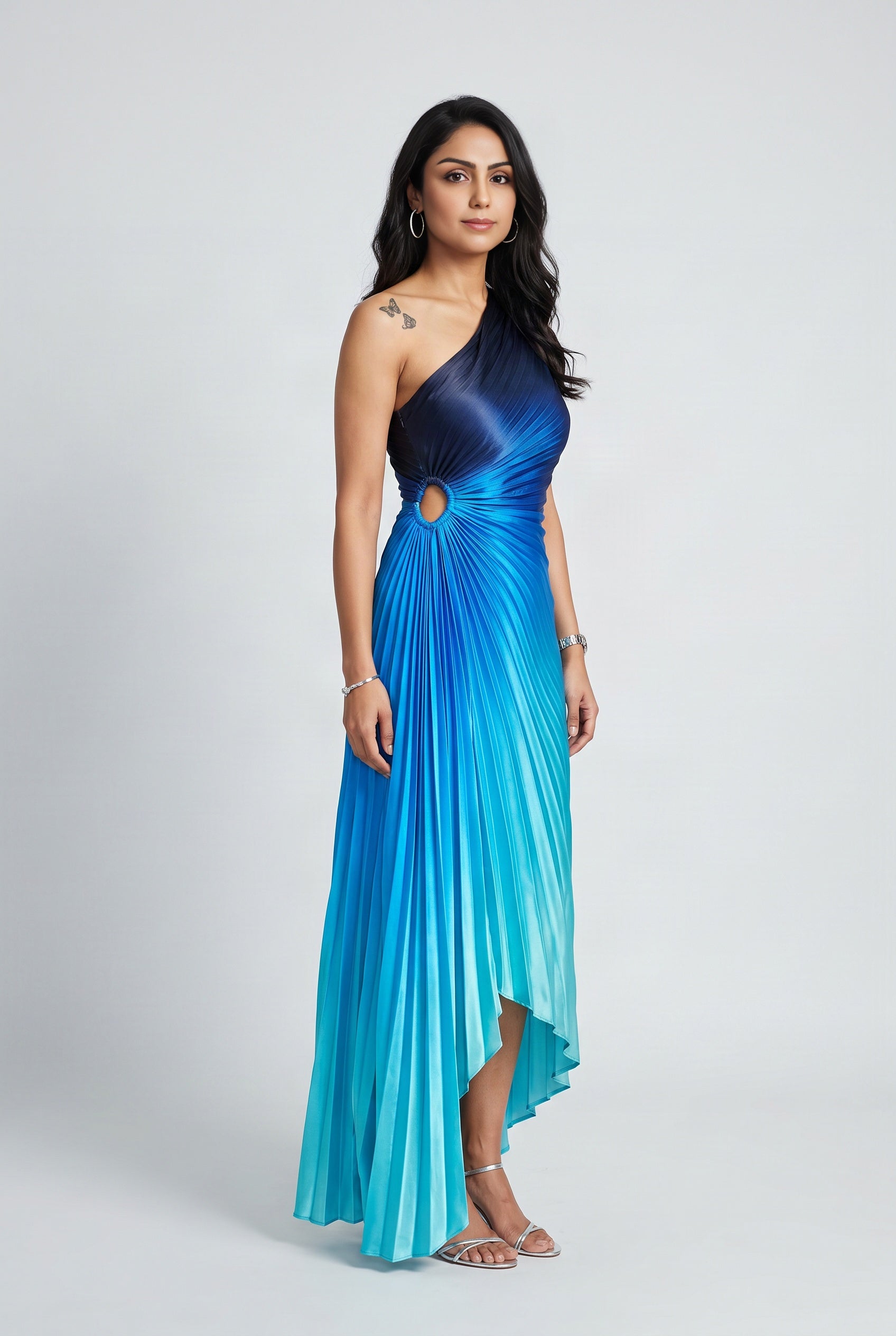 Angled side view of the blue ombre pleated maxi dress showing the waist cutout and uneven hem.