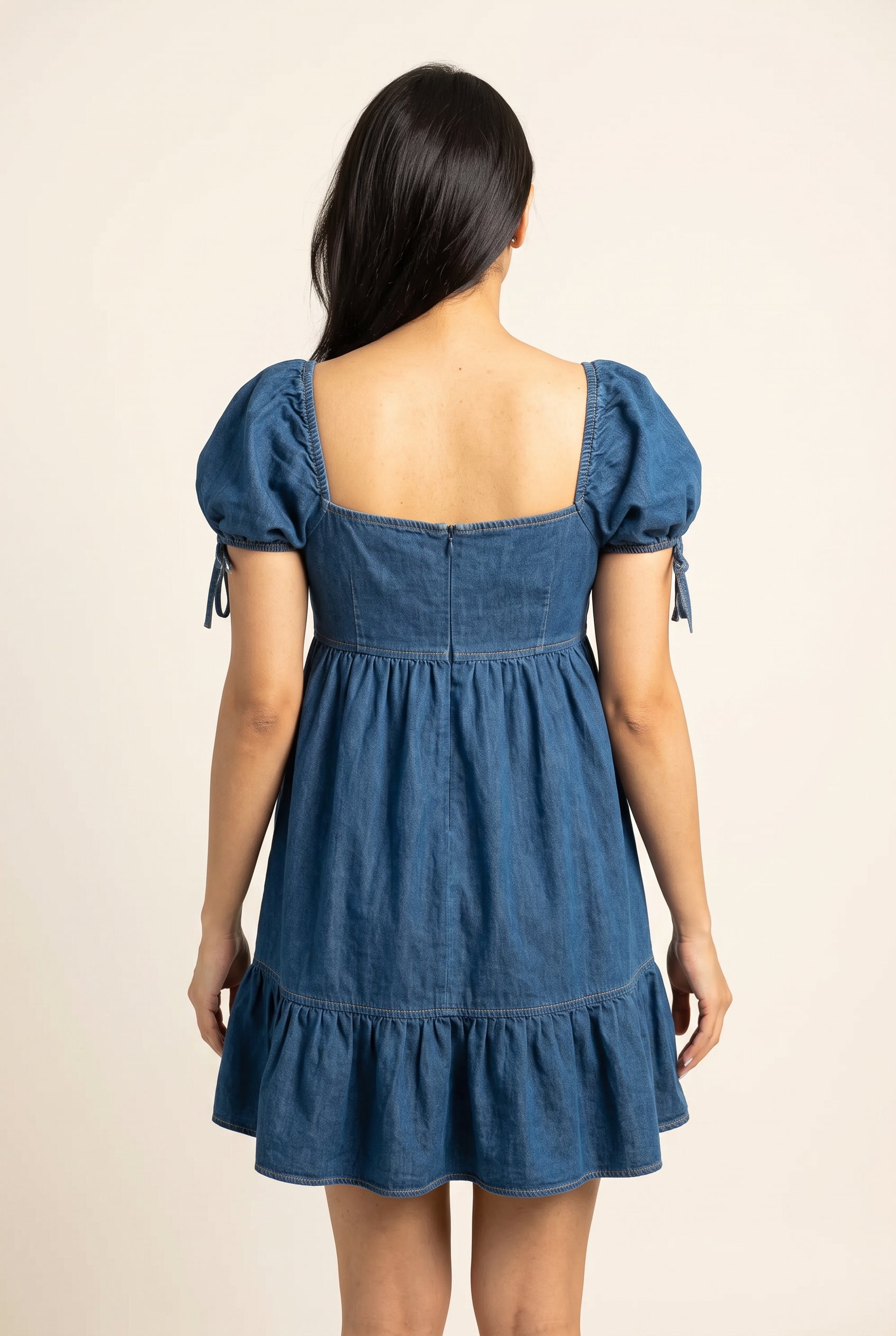 Back view of the blue denim babydoll mini dress showing the rear silhouette and puff sleeves.