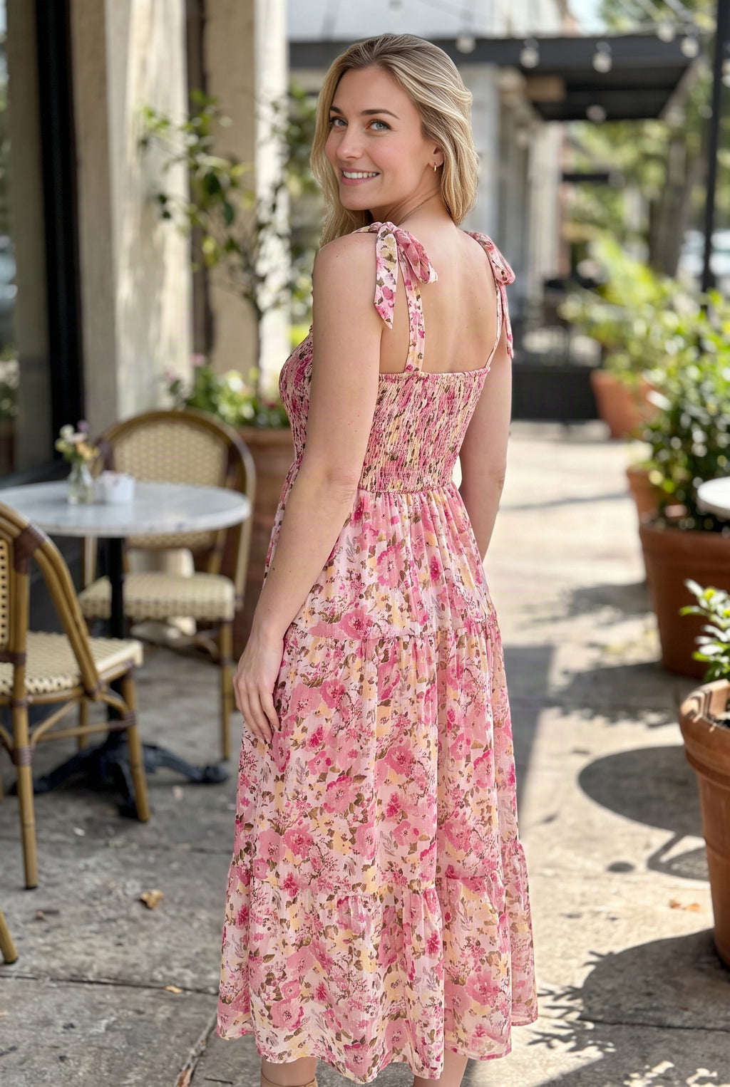 Rear three-quarter view of the floral maxi dress showing its square back, smocking and shoulder ties.