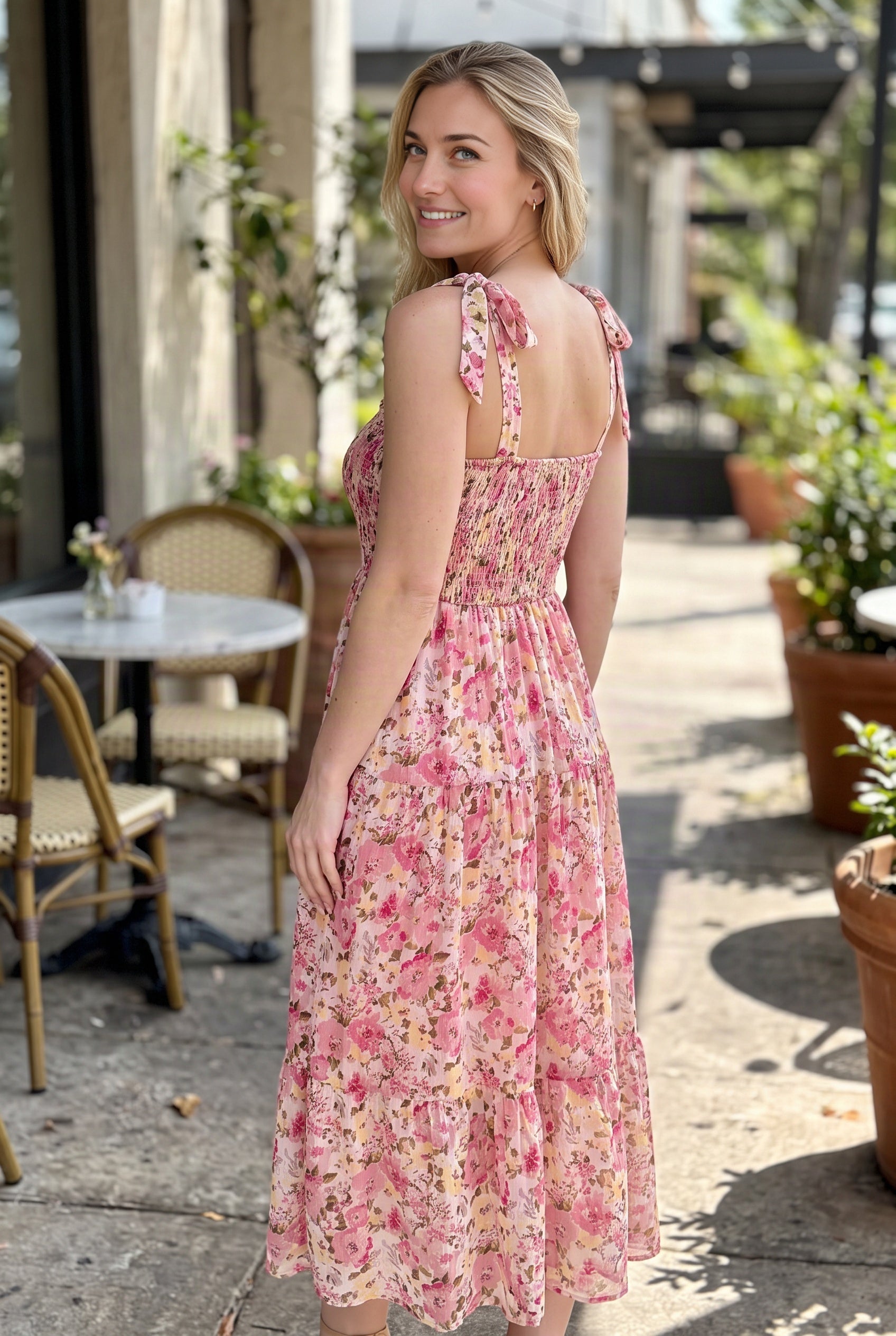 Rear three-quarter view of the floral maxi dress showing its square back, smocking and shoulder ties.
