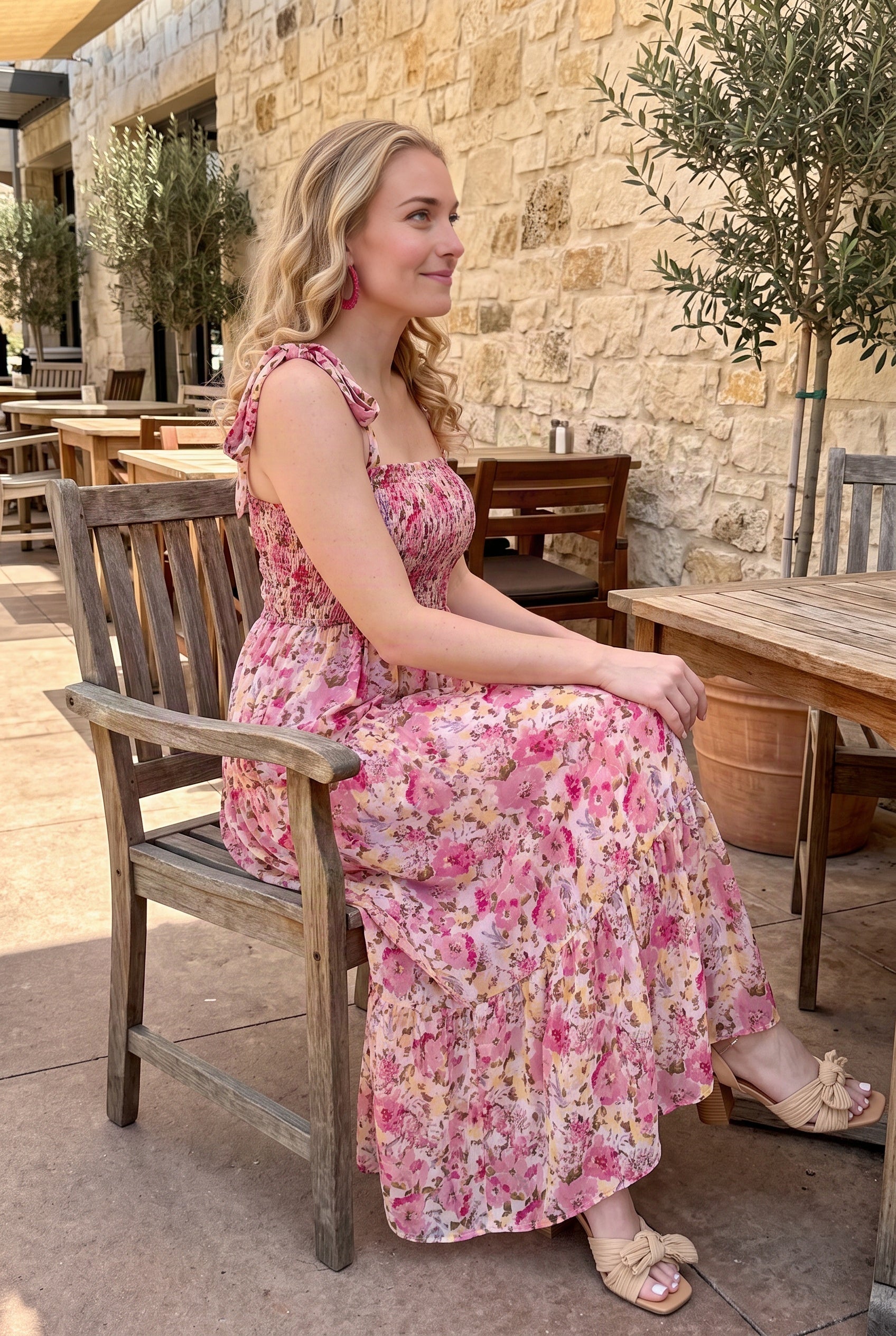 Seated side view of the floral maxi dress showing the smocked fit and how the tiered skirt settles.