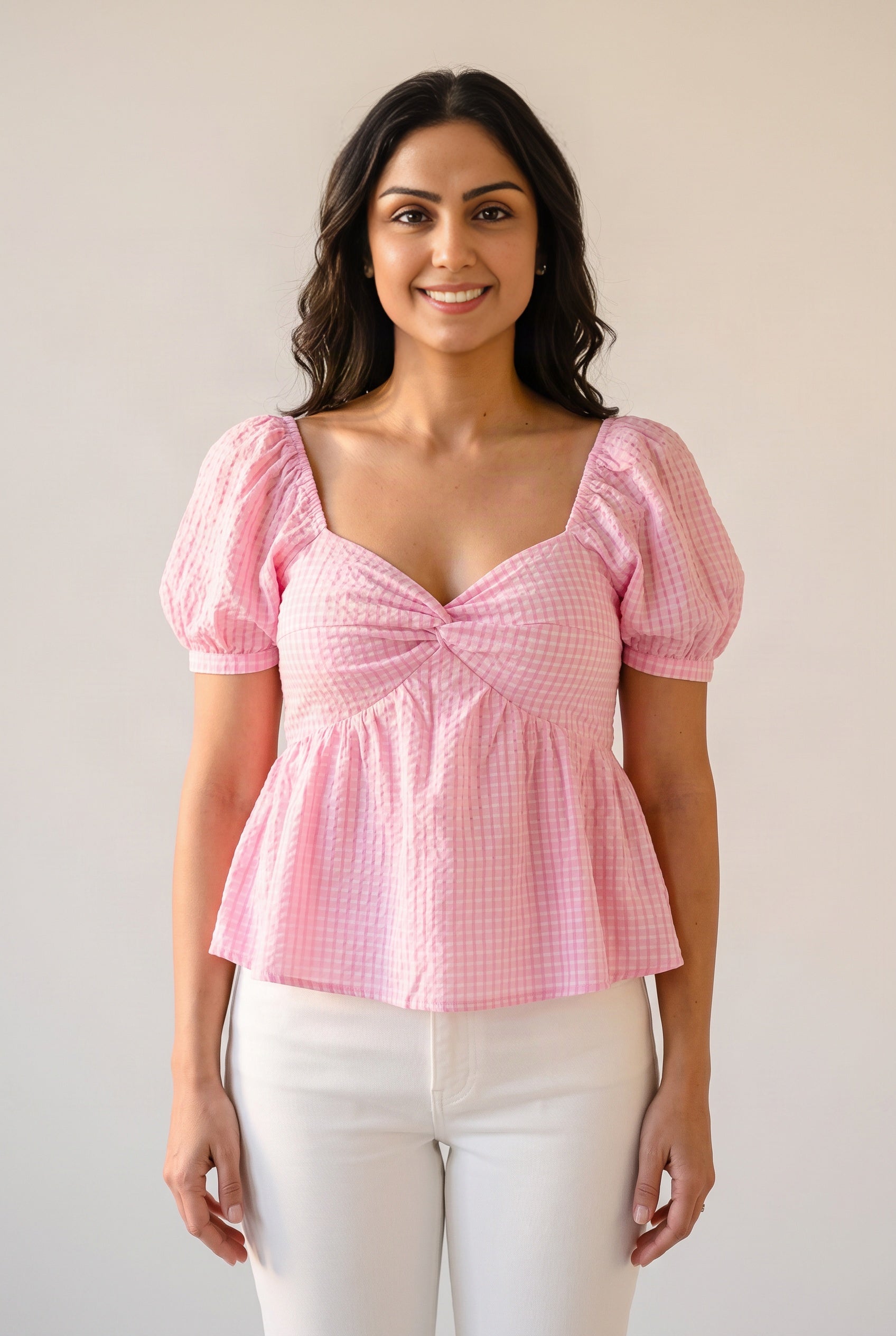 Front fit of the Blushing For You pink gingham top showing its puff sleeves, fitted bodice and peplum.