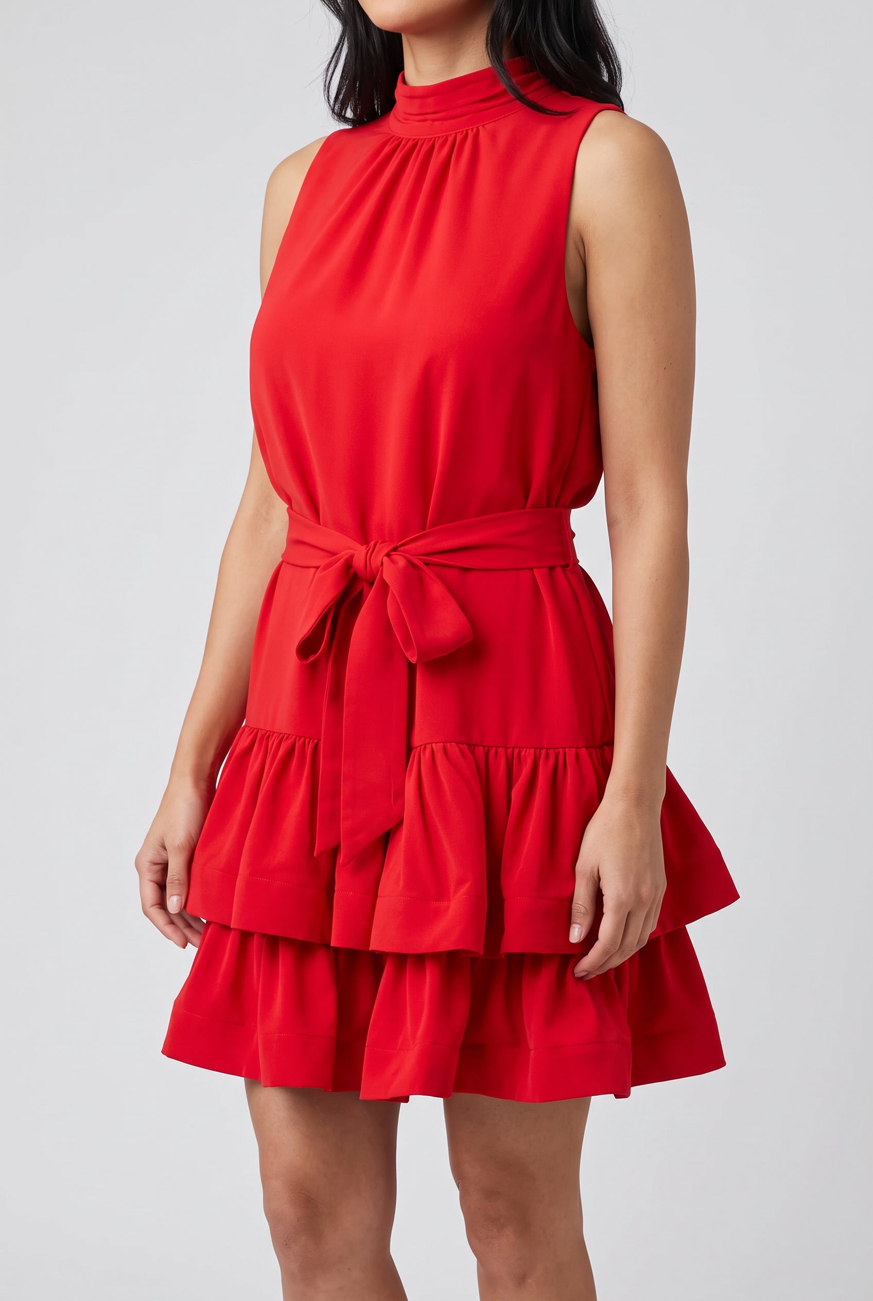 Close view of the red mini dress showing its smooth fabric, gathered tiers and opacity.