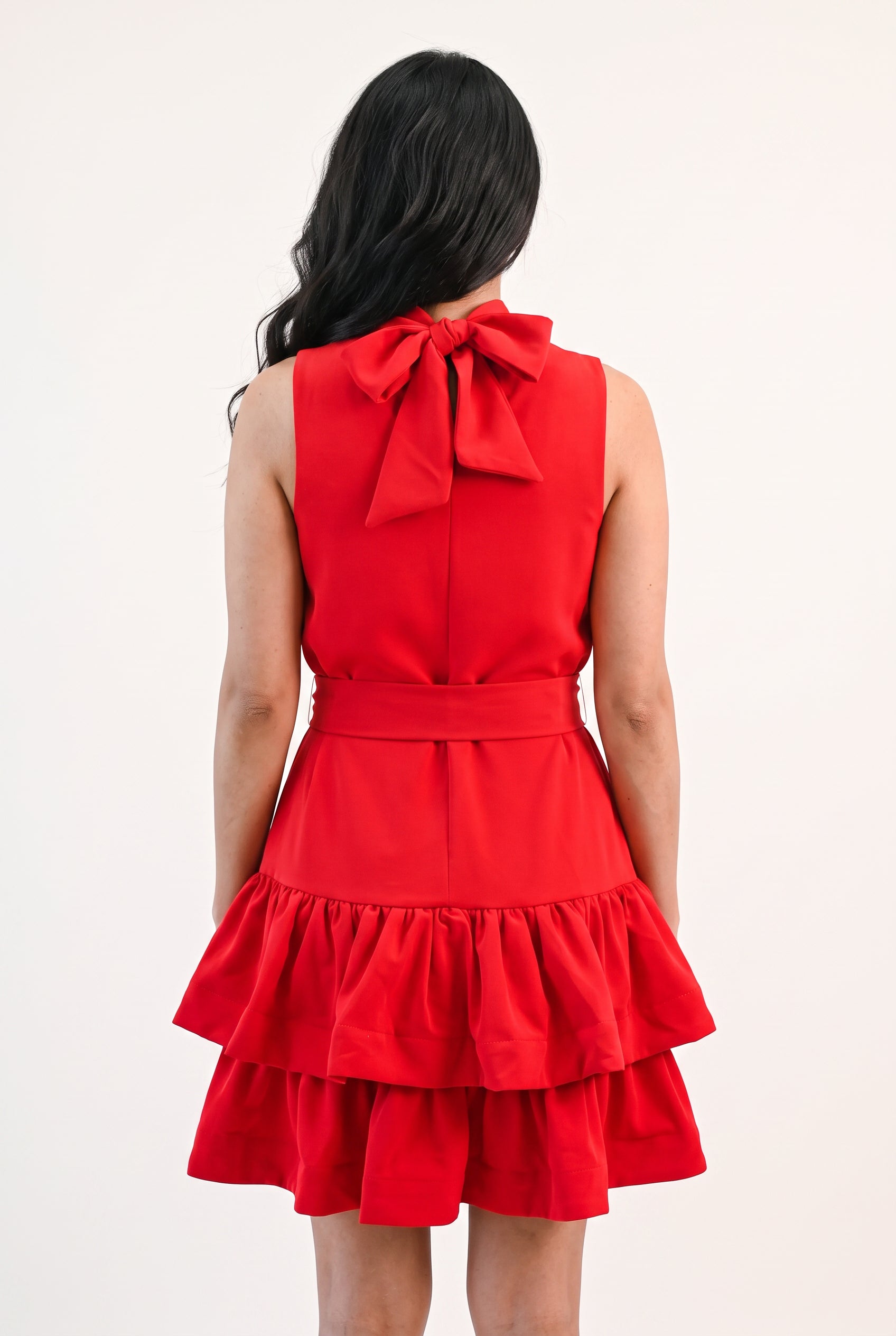 Full back of the red ruffle tiered mini dress showing the neck bow, waist and complete hem.