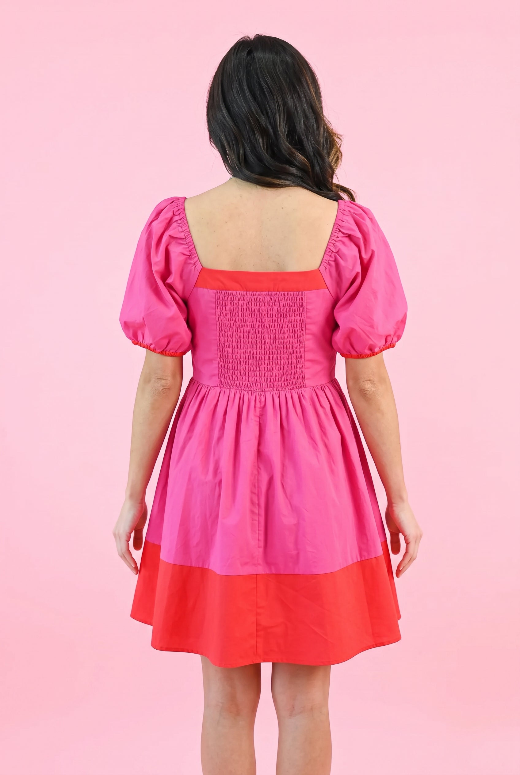 Back fit of the Small magenta dress showing the low square neckline and stretch smocking.