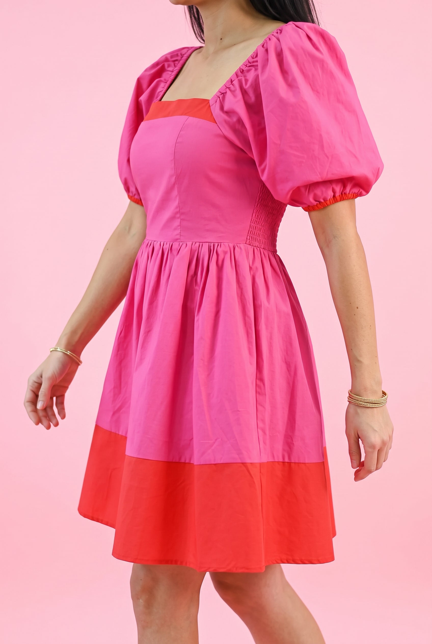 Close view of the magenta dress showing its crisp fabric, waist gathers and opacity in controlled light.