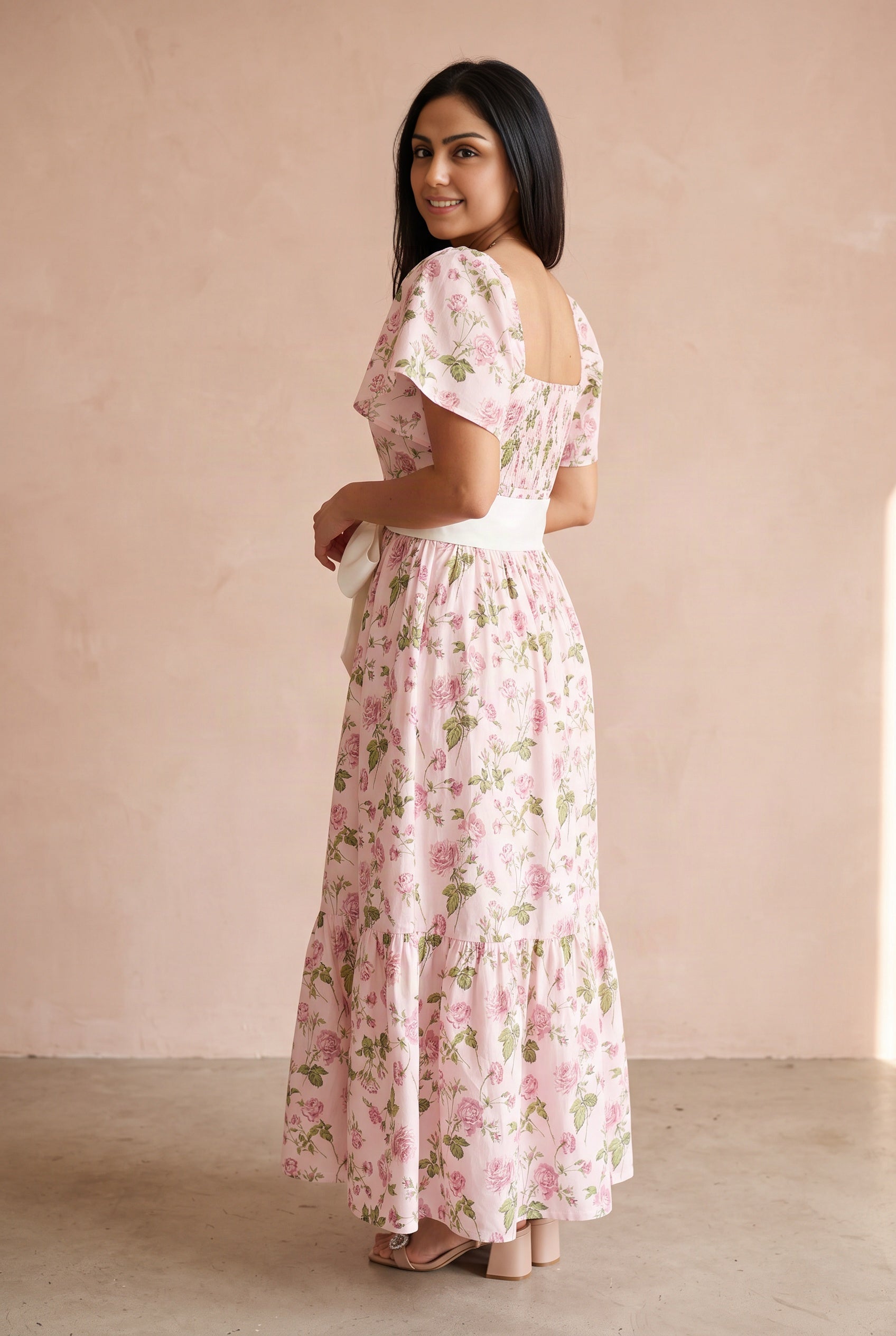 Angled side view of the pink floral maxi dress showing its fitted bodice, flutter sleeve, and skirt depth.