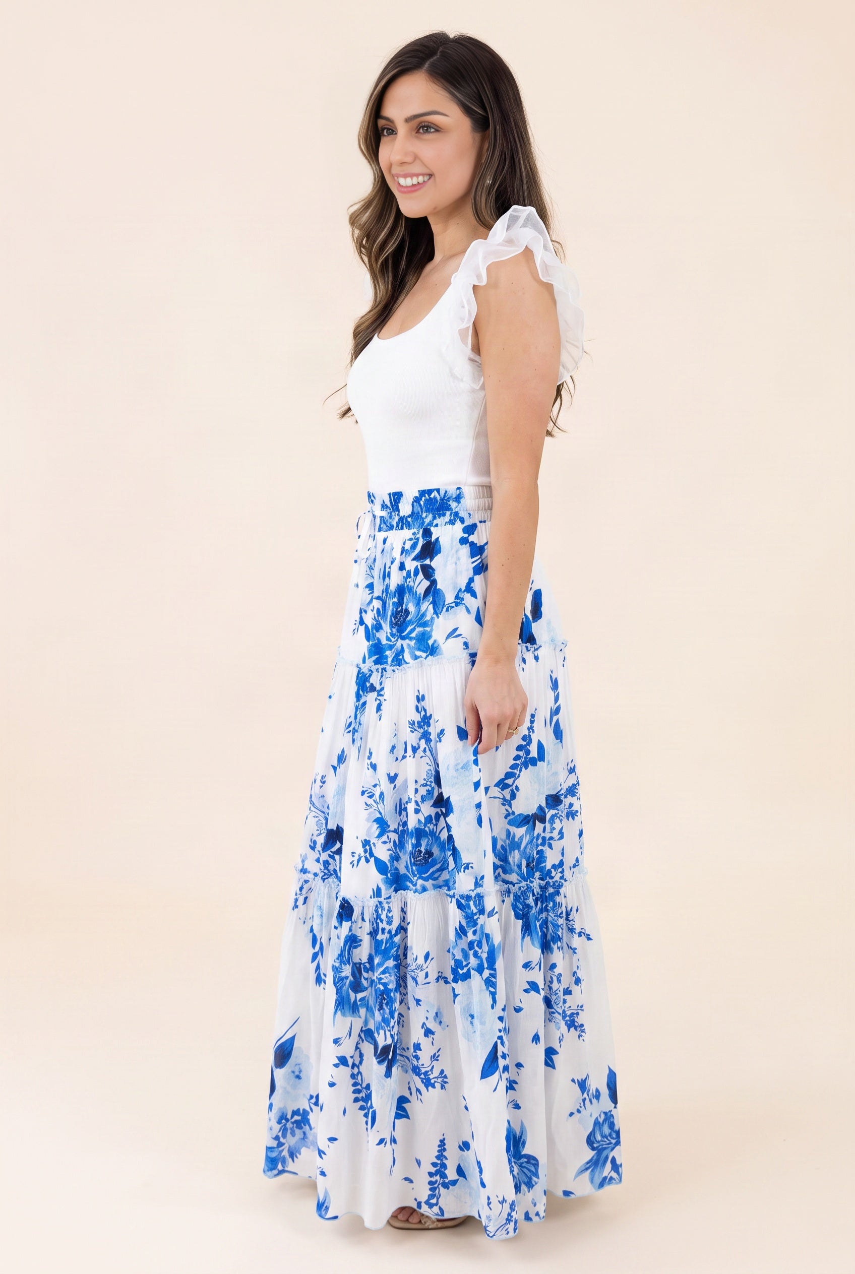 Angled side fit of the blue floral tiered maxi skirt showing its waistband, hip volume, and maxi drape.