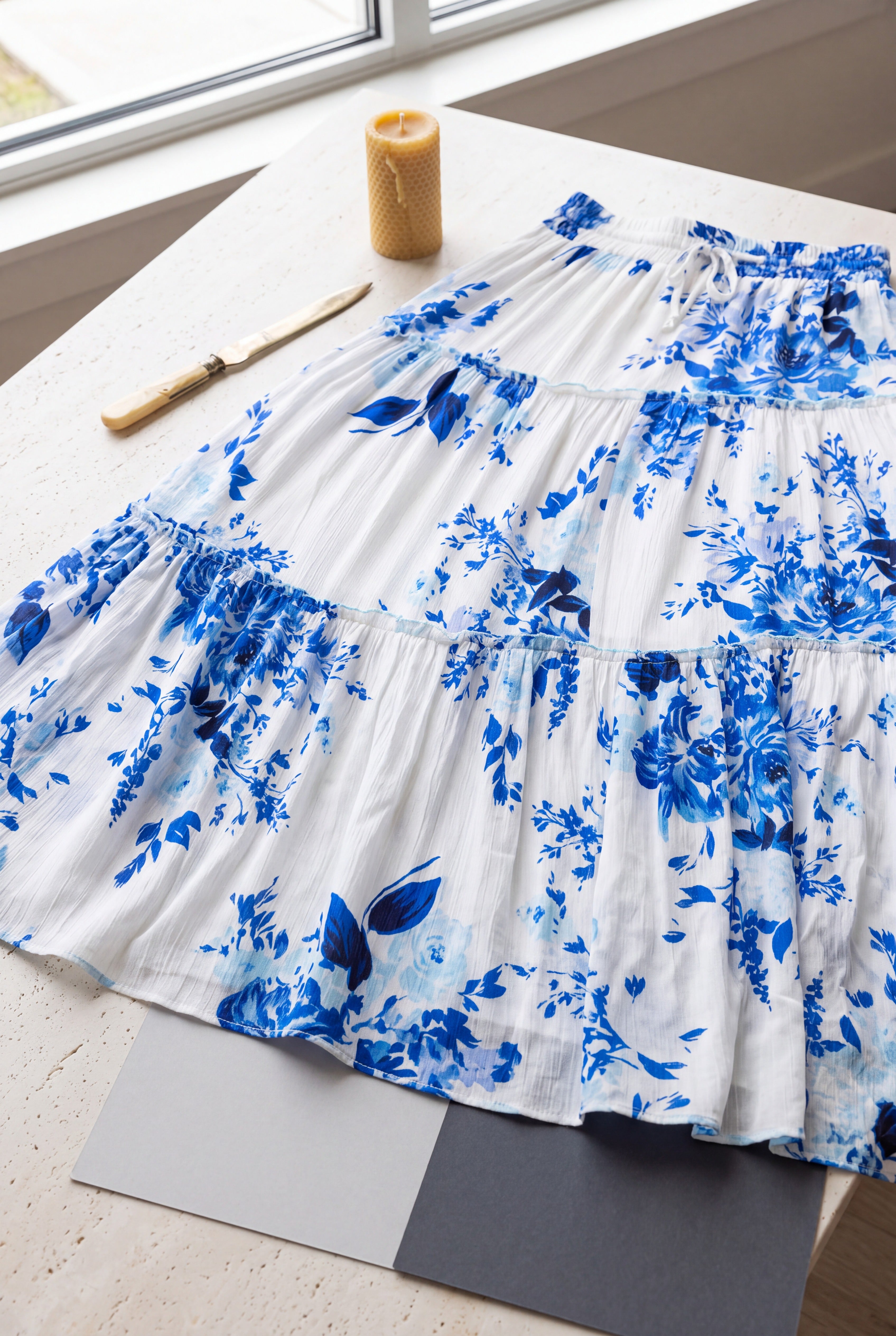 Close detail of the blue floral maxi skirt showing its crinkled fabric, tier seam, and visible transparency.