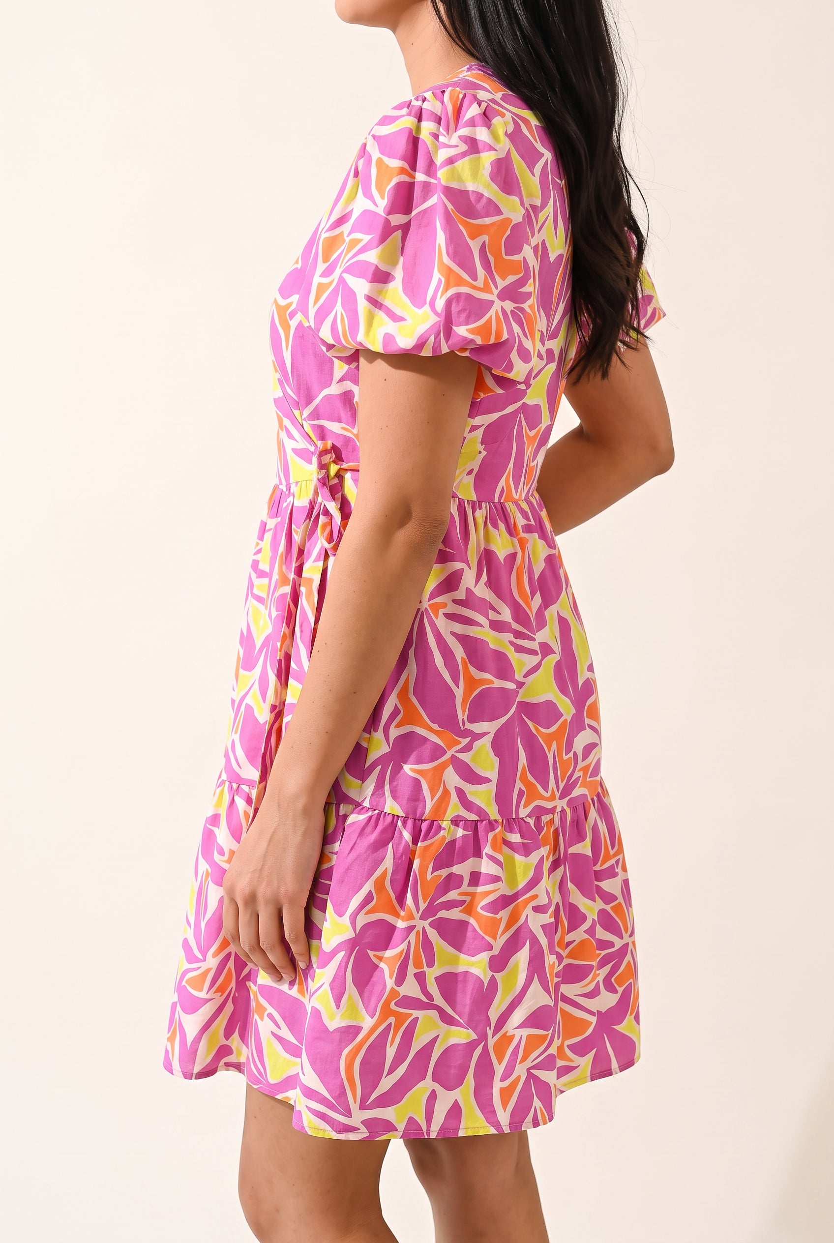 Angled side fit of the Somewhere Sunny floral dress showing its puff sleeve and short tiered skirt.