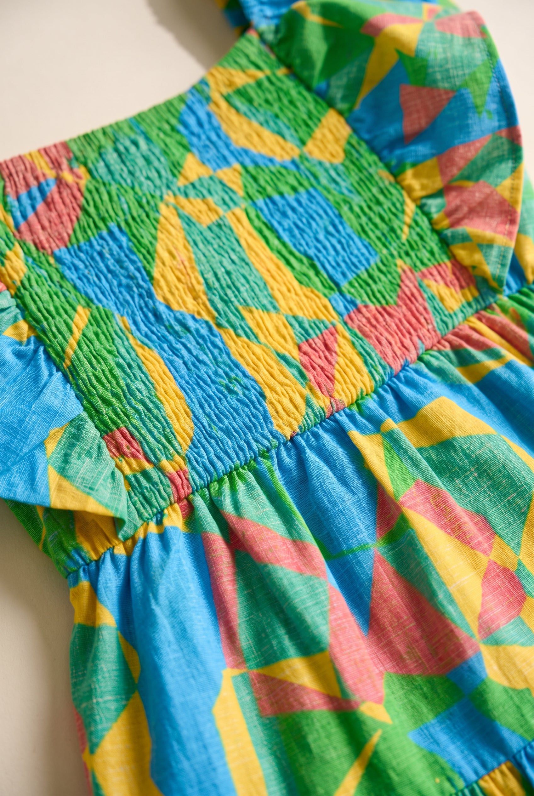 Close detail of the dress showing elastic smocking, gathered waist seam and woven geometric fabric.