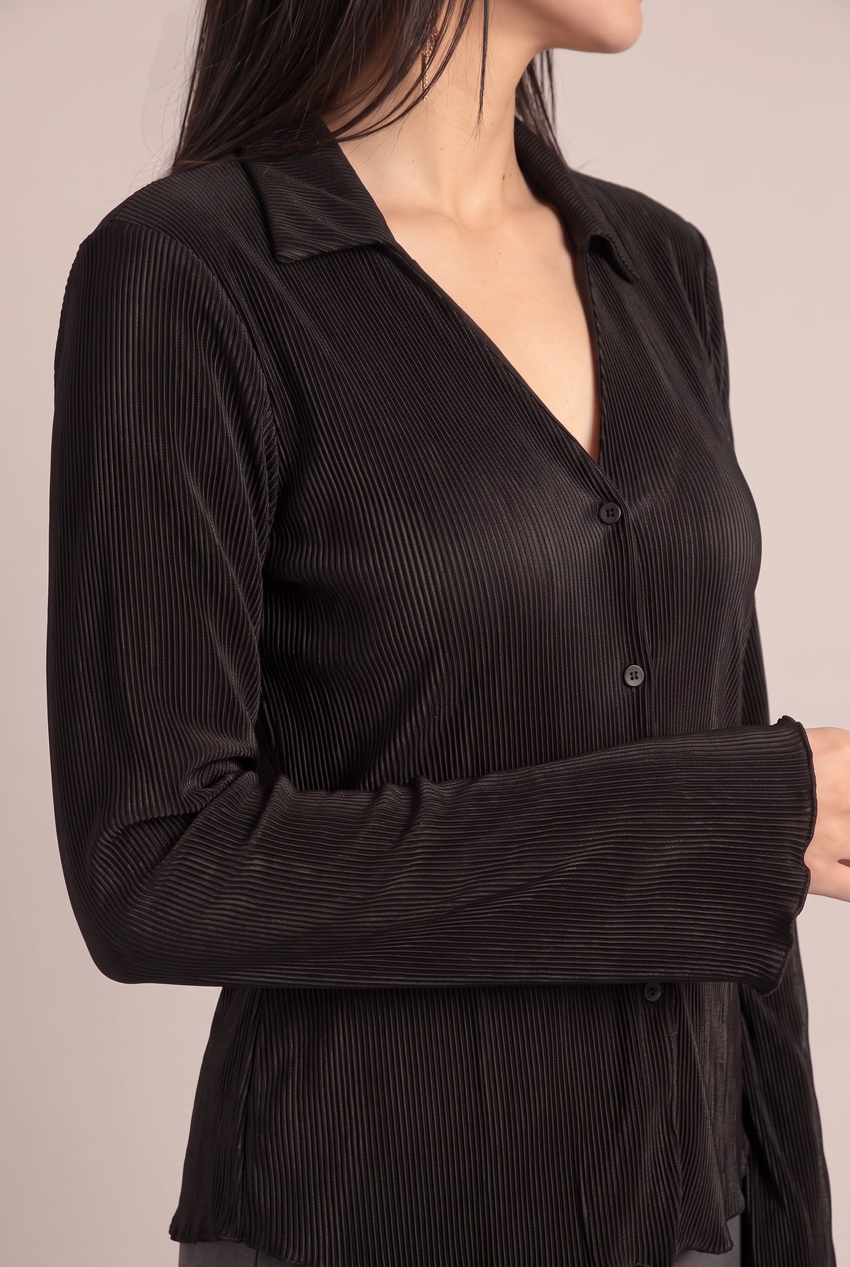 Close fit detail of the Black pleated top showing the collar, tonal buttons, fine pleats, and fluted sleeve edge.