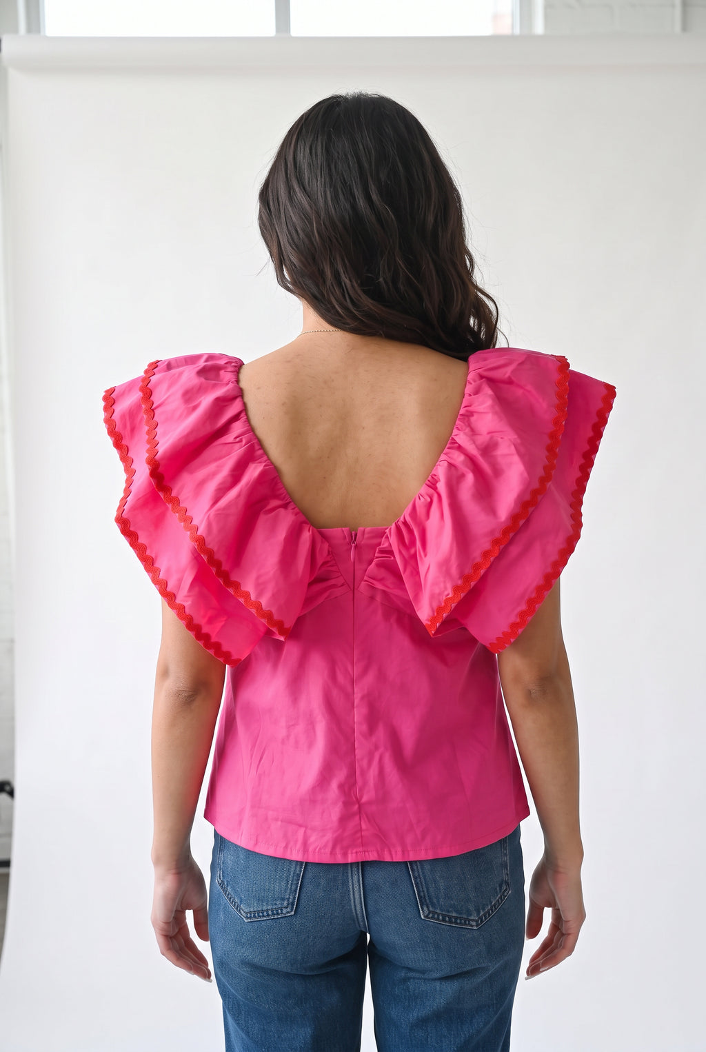 Back view of the pink ruffle babydoll top showing the low scoop, layered collar, and concealed zipper.