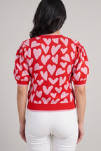 Back fit of the Love Knows All heart sweater in Small, showing the rear motif, puff sleeves, and ribbed hem.