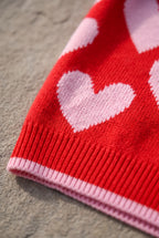Macro detail of the red and pink heart sweater showing knitted-in colorwork and pink-tipped ribbing.