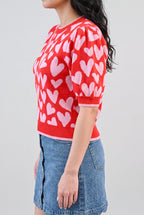 Angled side fit of the heart sweater in Small, showing puff-sleeve depth, cuff fit, and body length.