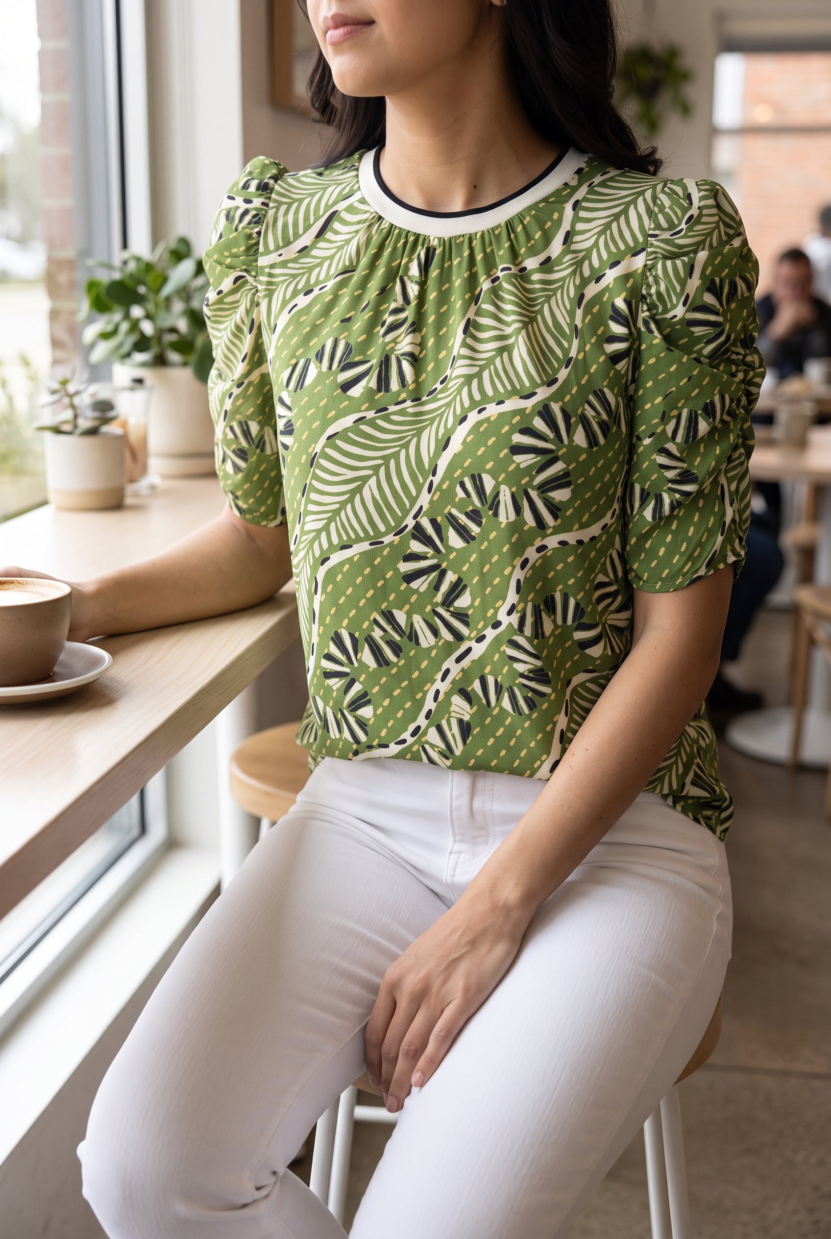 Green puff sleeve top in Small styled with white jeans at a café, showing its relaxed seated drape.