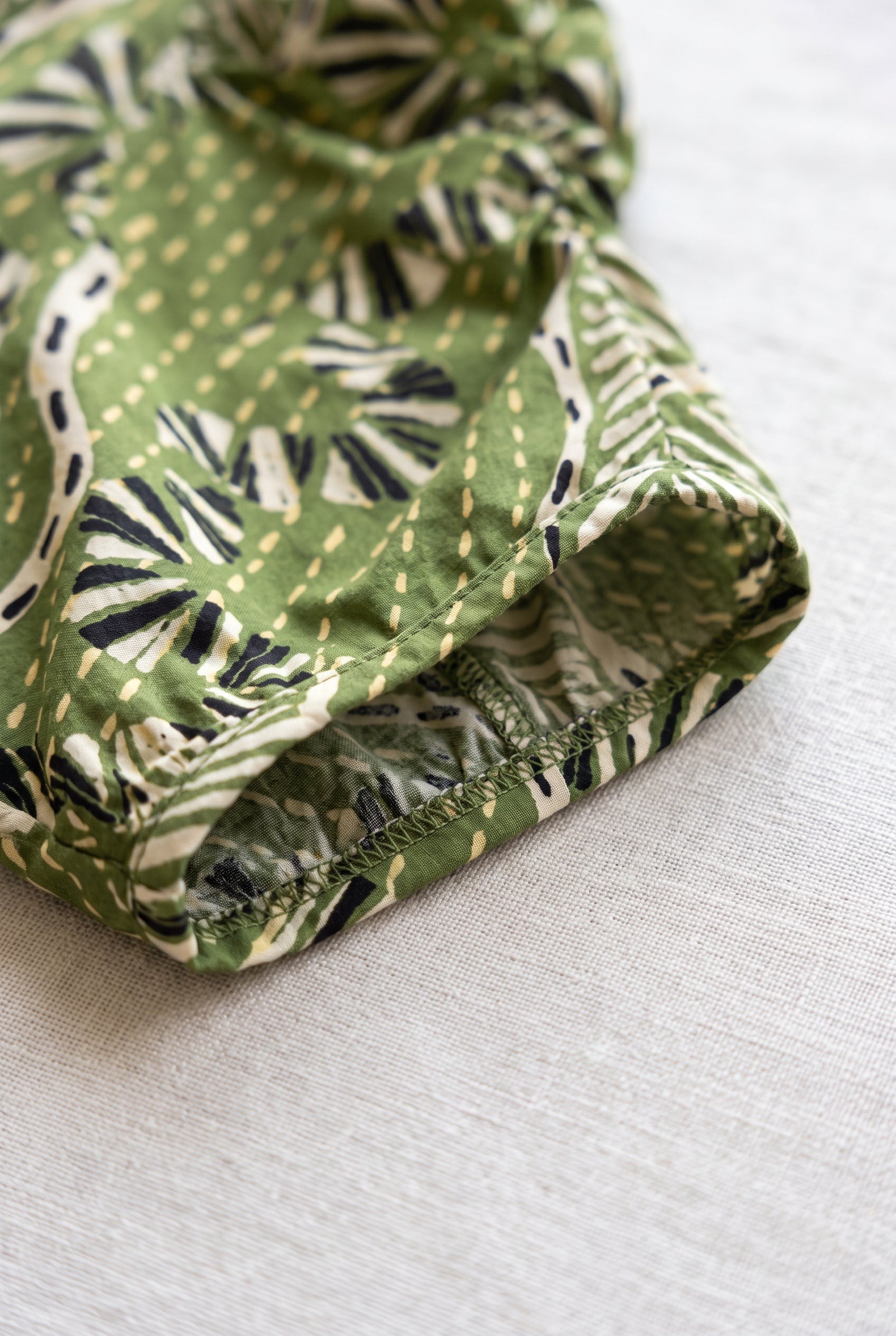 Puff sleeve detail of the green printed top showing its gathered opening, weave and interior finish.