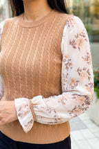 Close detail of the sweater top’s cable knit, translucent floral sleeve, wrist band, and ruffle cuff.