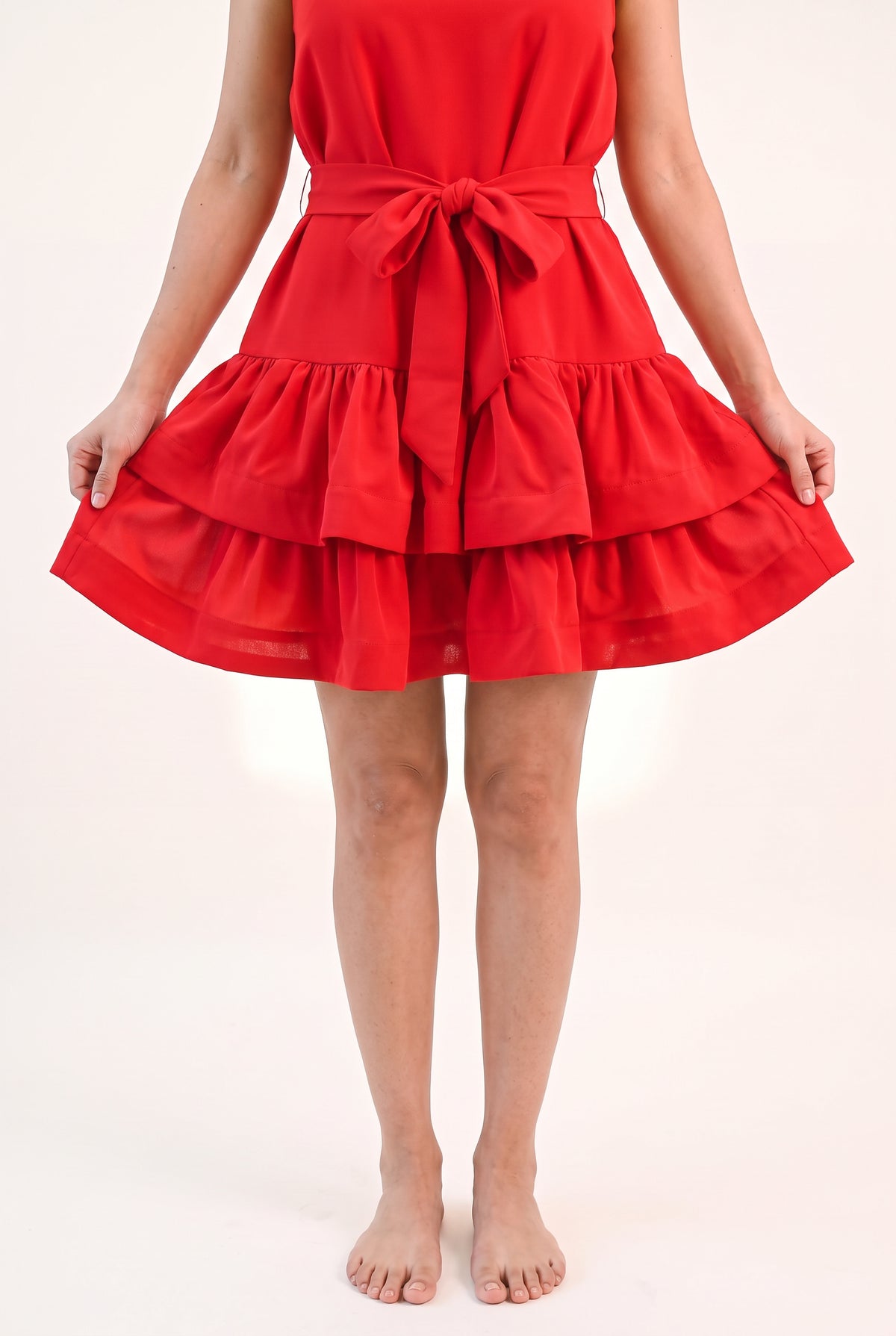 Close view of the red mini dress showing fabric opacity, low sheen and tiered ruffle hems.