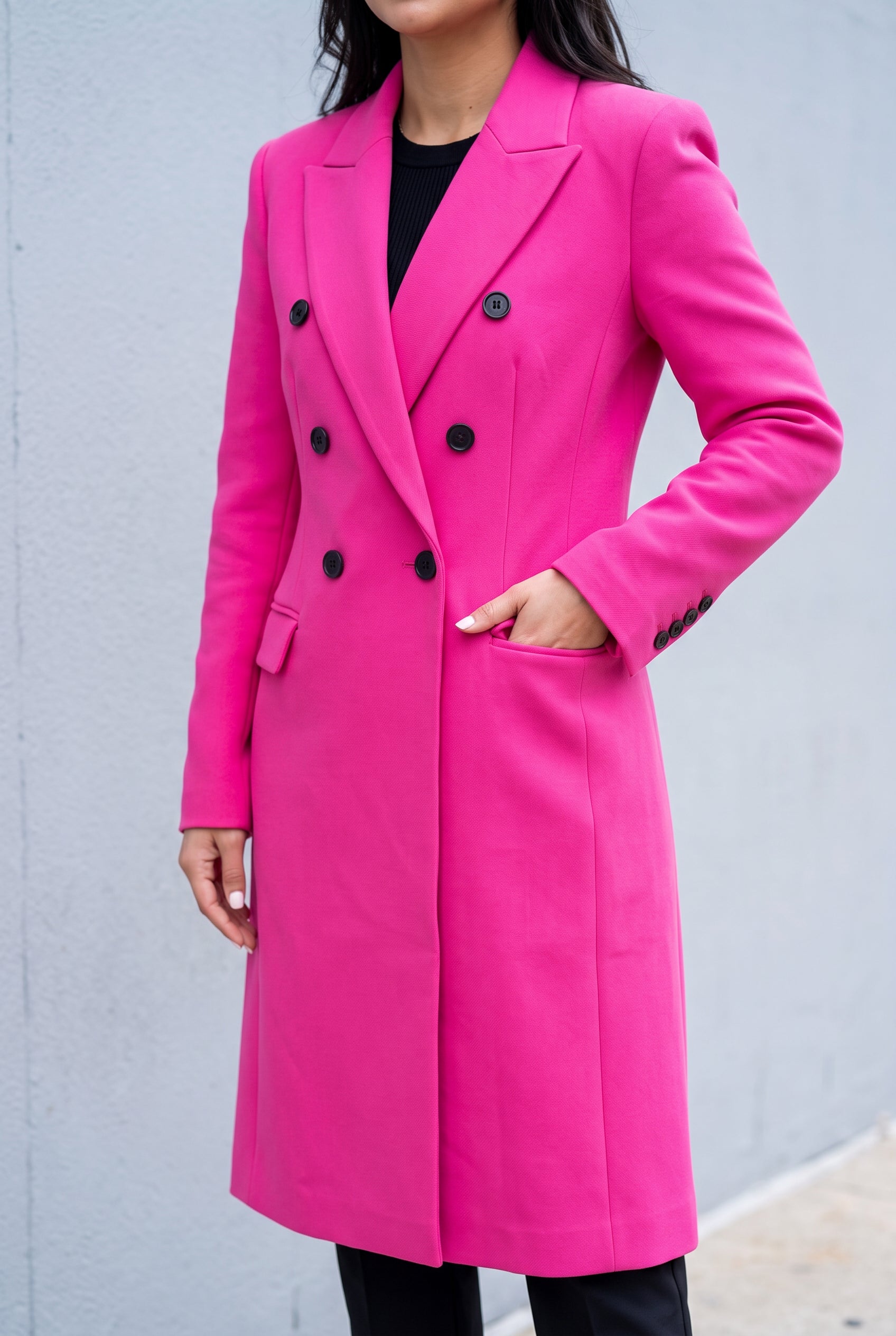 Hot pink coat with a hand inside the functional flap pocket, showing its entry position.