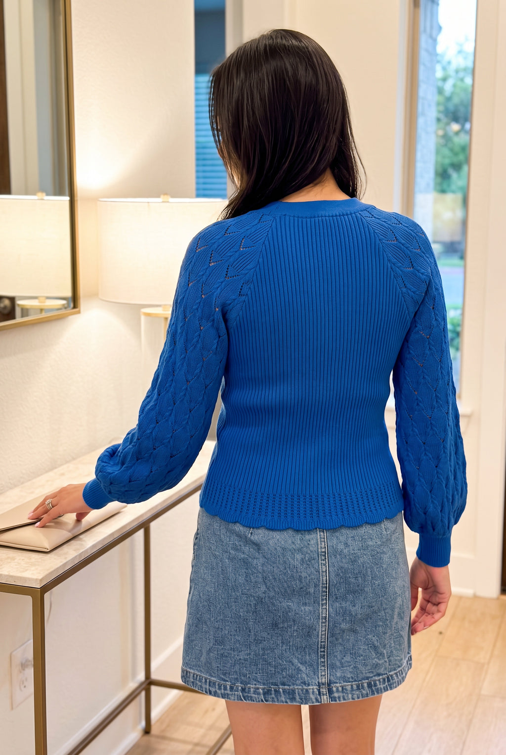 Rear three-quarter view of the Tell Me About It Sweater Top moving during a natural reach.