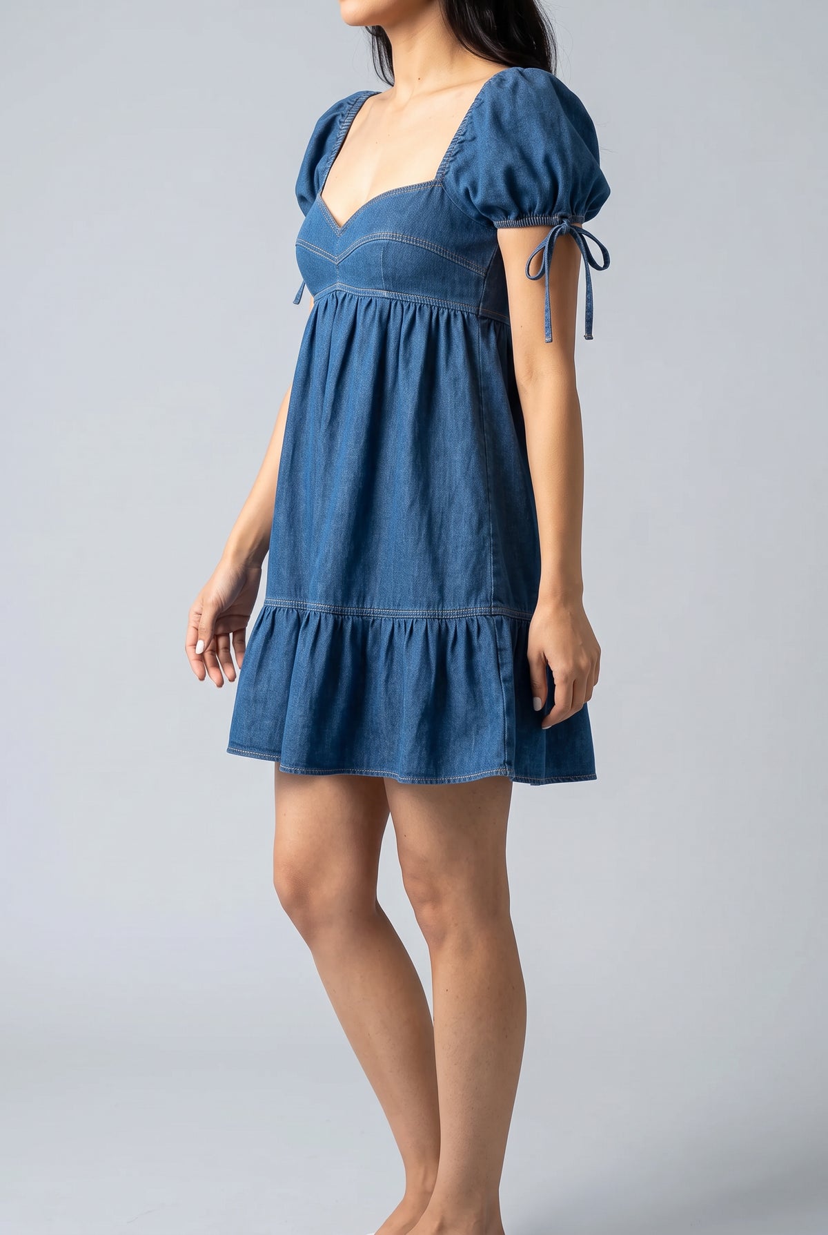 Side fit of the blue denim babydoll mini dress on Shweta in size Small.