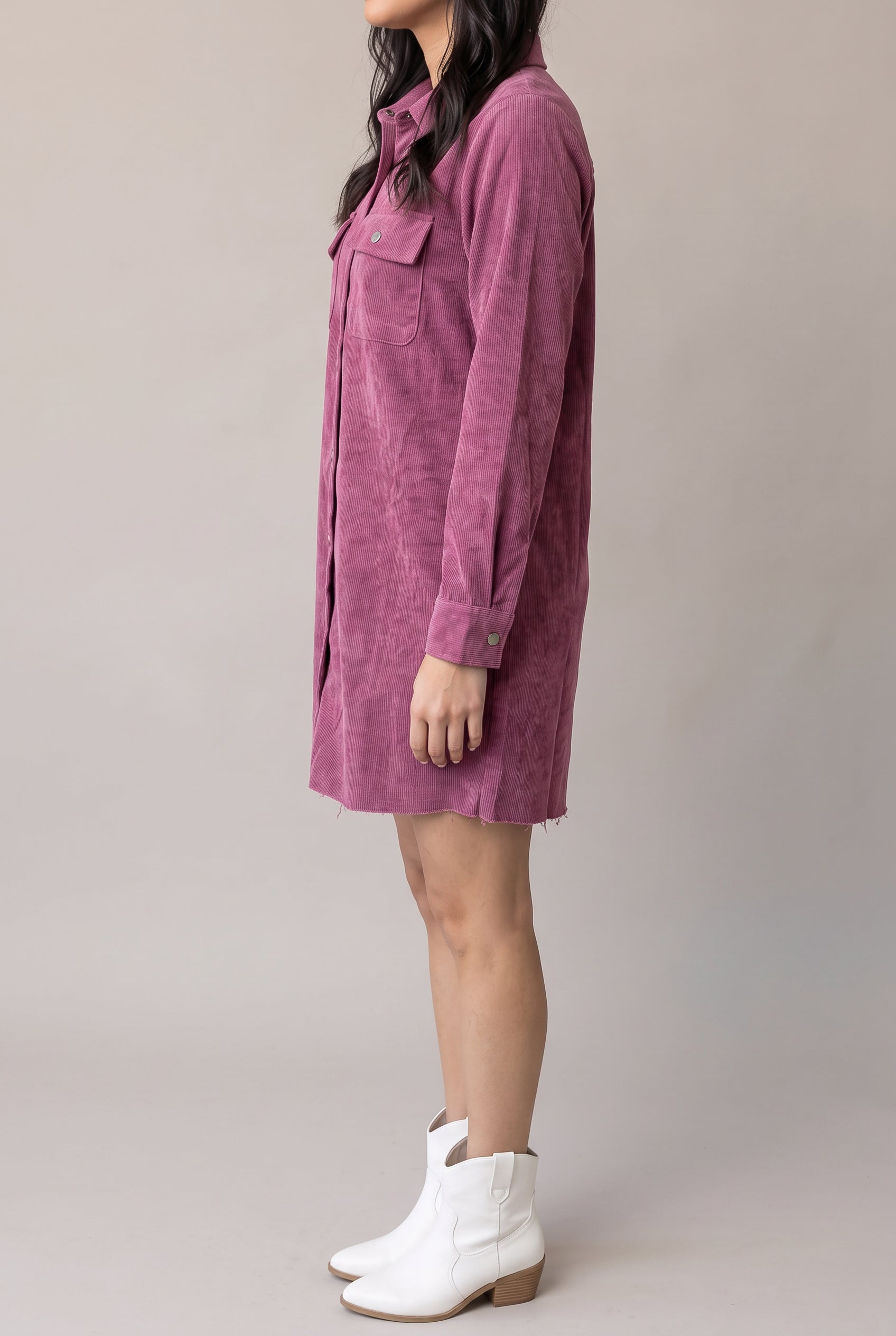 Angled side view of the Small mauve corduroy shirt dress showing its loose waist, cuff and side opening.