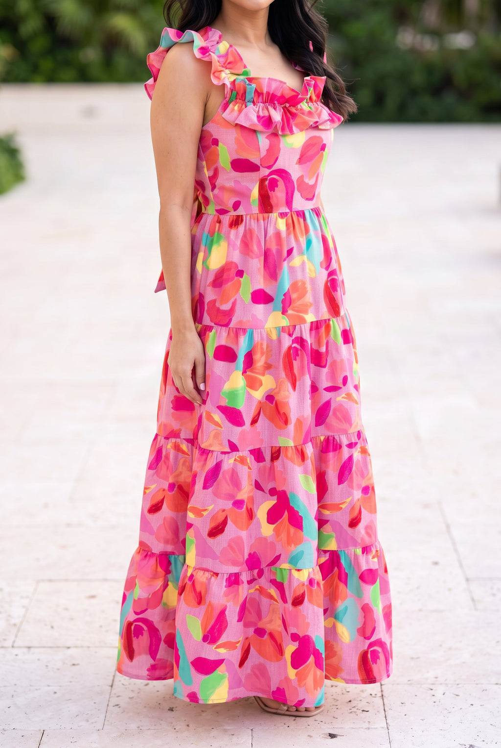 Blooming Affair floral maxi dress worn on a sunny patio, showing the ruffled neckline and ankle length tiers.