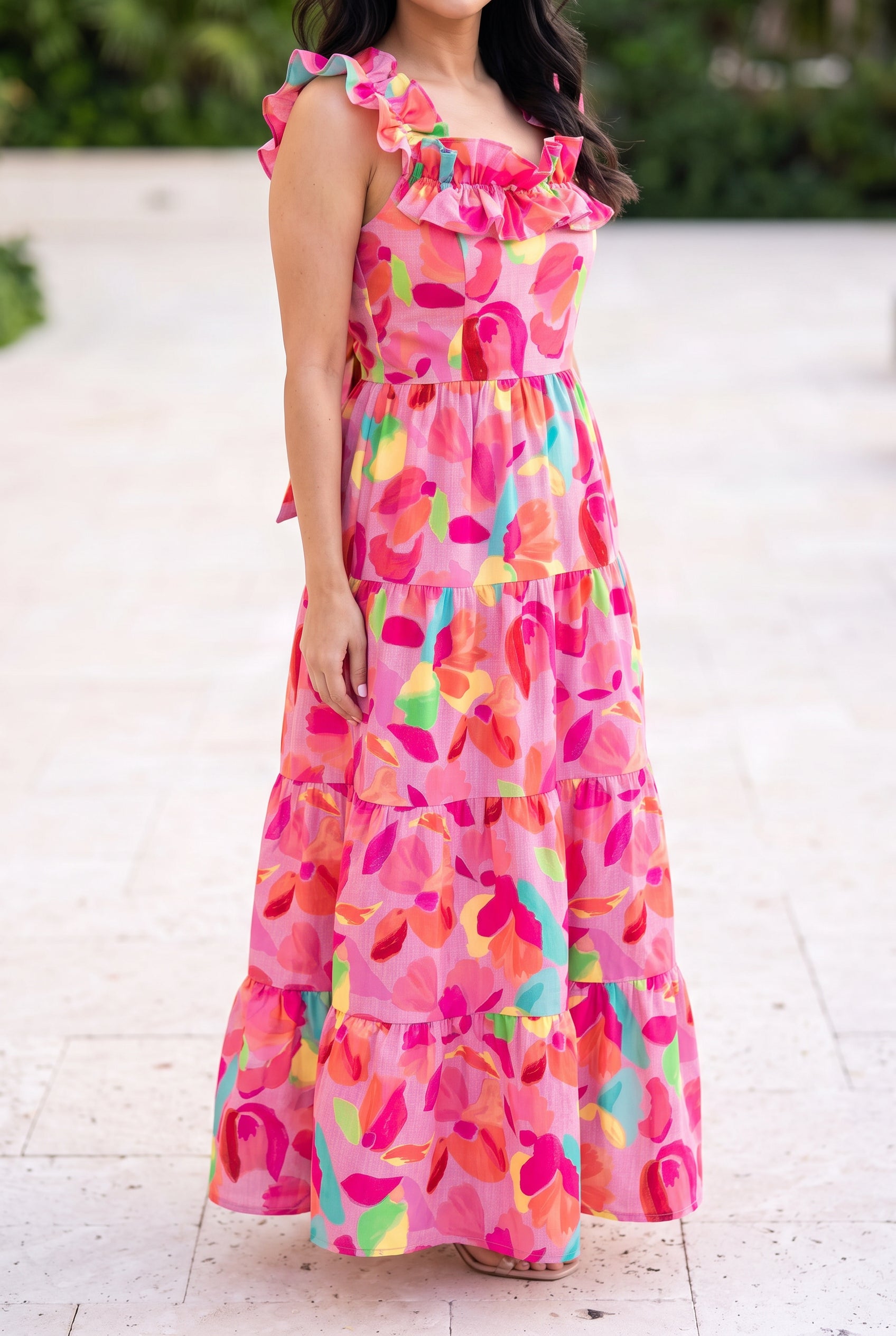 Blooming Affair floral maxi dress worn on a sunny patio with its tiered skirt falling at full length.