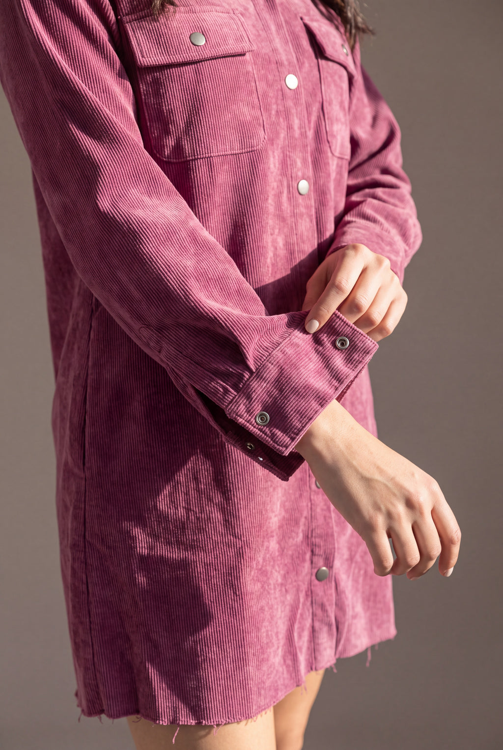 Close detail of the mauve corduroy ribs, washed finish, chest pocket, metal snaps and wide shirt cuff.