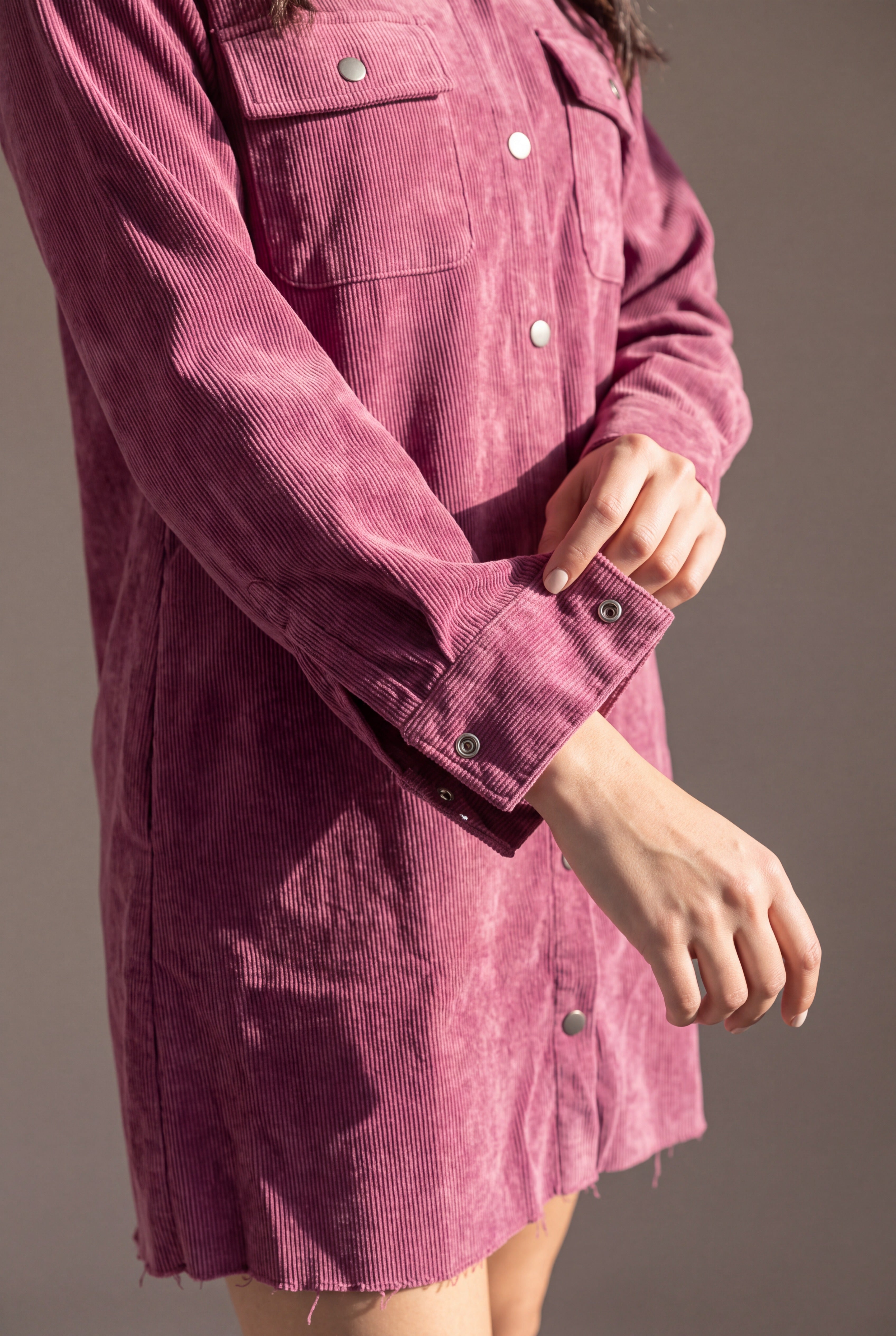Close detail of the mauve corduroy ribs, washed finish, chest pocket, metal snaps and wide shirt cuff.