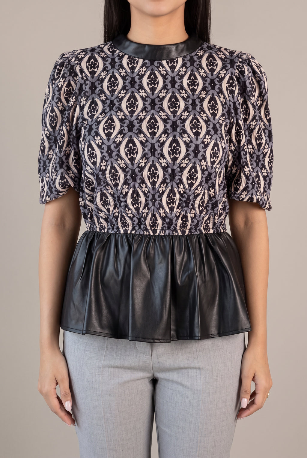 Close view of the Last Night peplum top showing its gathered waist seam and faux leather finish.